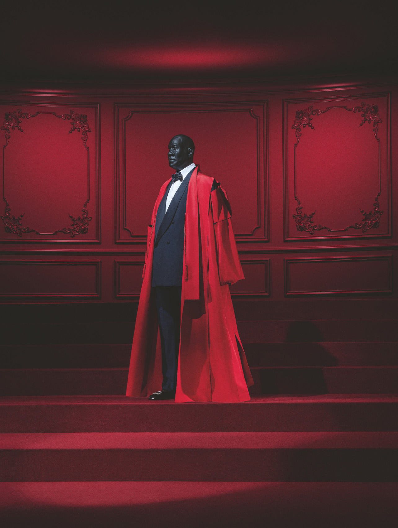 A portrait of fashion stylist, Andre Leon Talley dressed in a black suite and red jacket gown