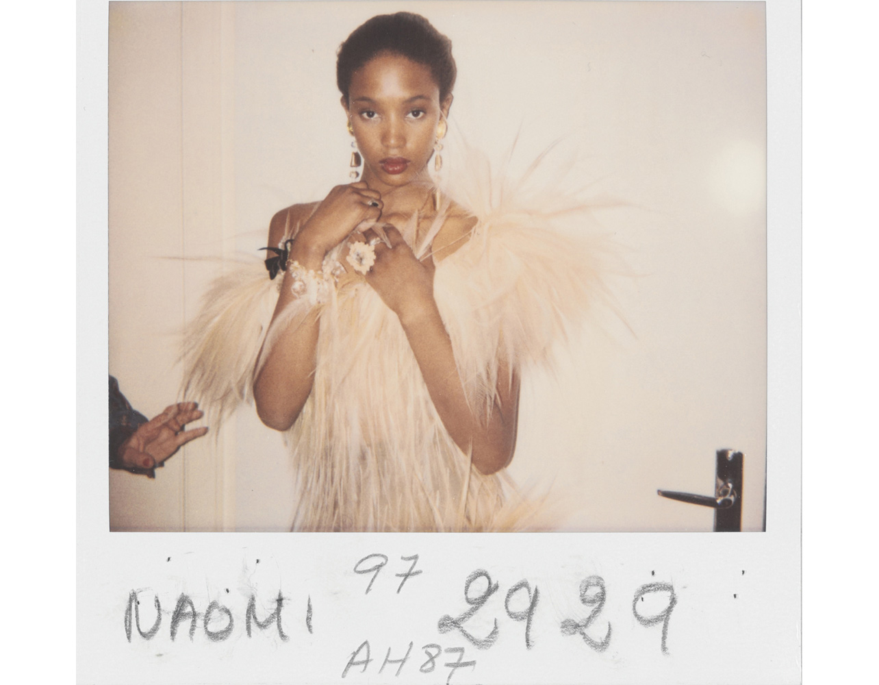Fashion model Naomi Campbell in a feathered dress captured in a Polaroid, featured in the book Yves Saint Laurent and Photography