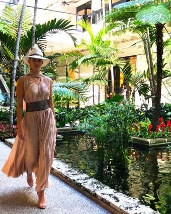 Model strolling by the signature Bal Harbour koi ponds wearing a Fabiana Filippi pleated nude chiffon dress