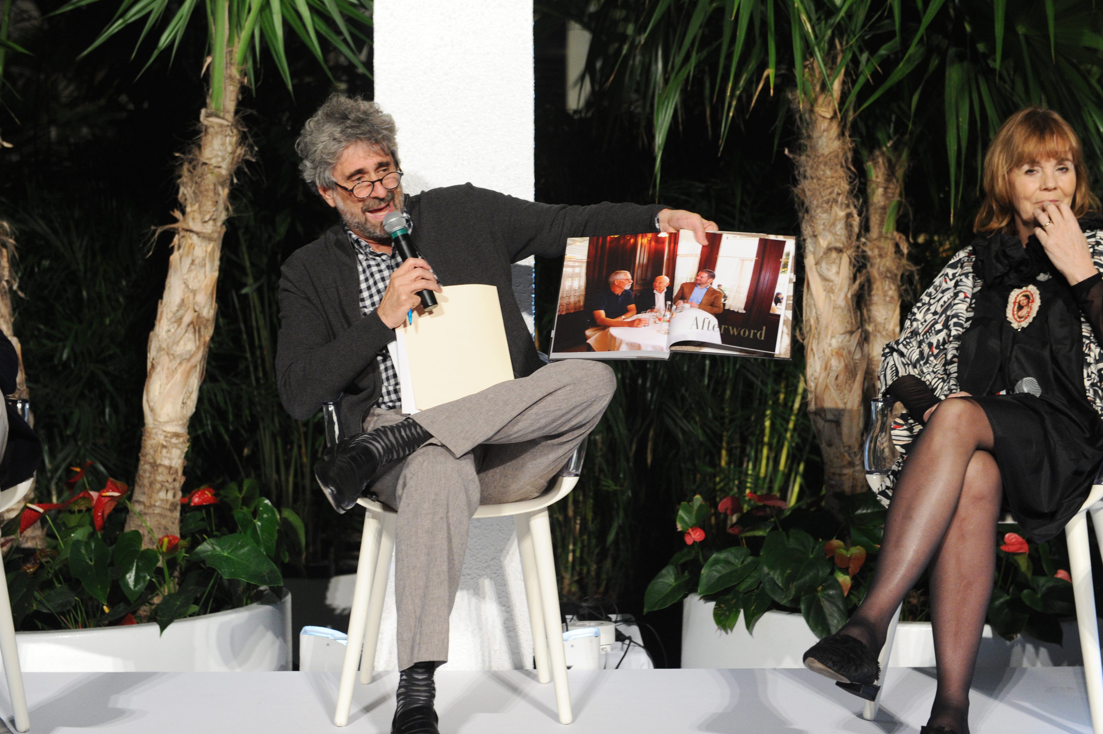 Speaker Mitchell Kaplan displaying Theater of Shopping book to audience