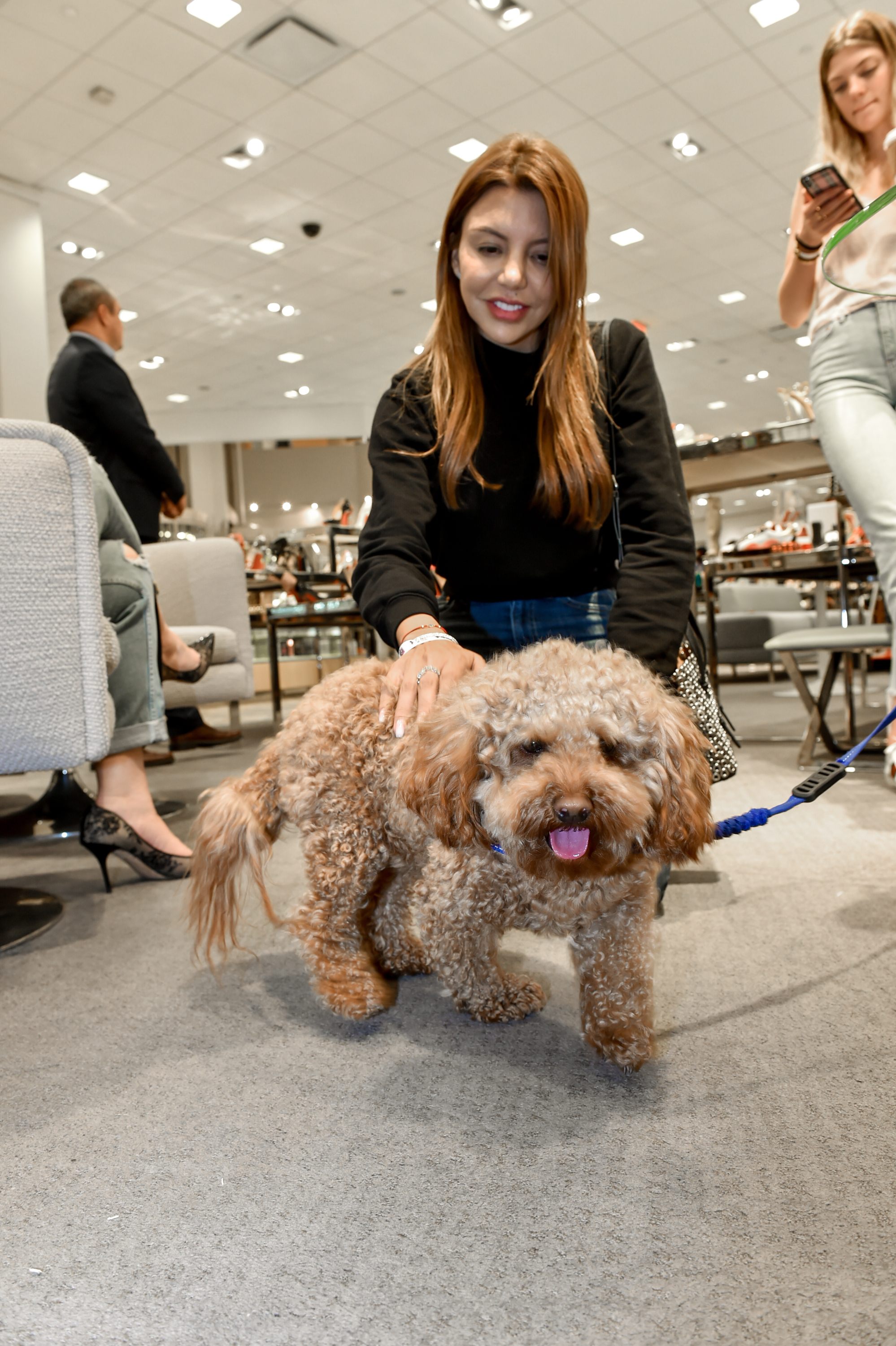 Guest petting her dog during the Walk in Style for the Animals Event inside Neiman Marcus Bal Harbour