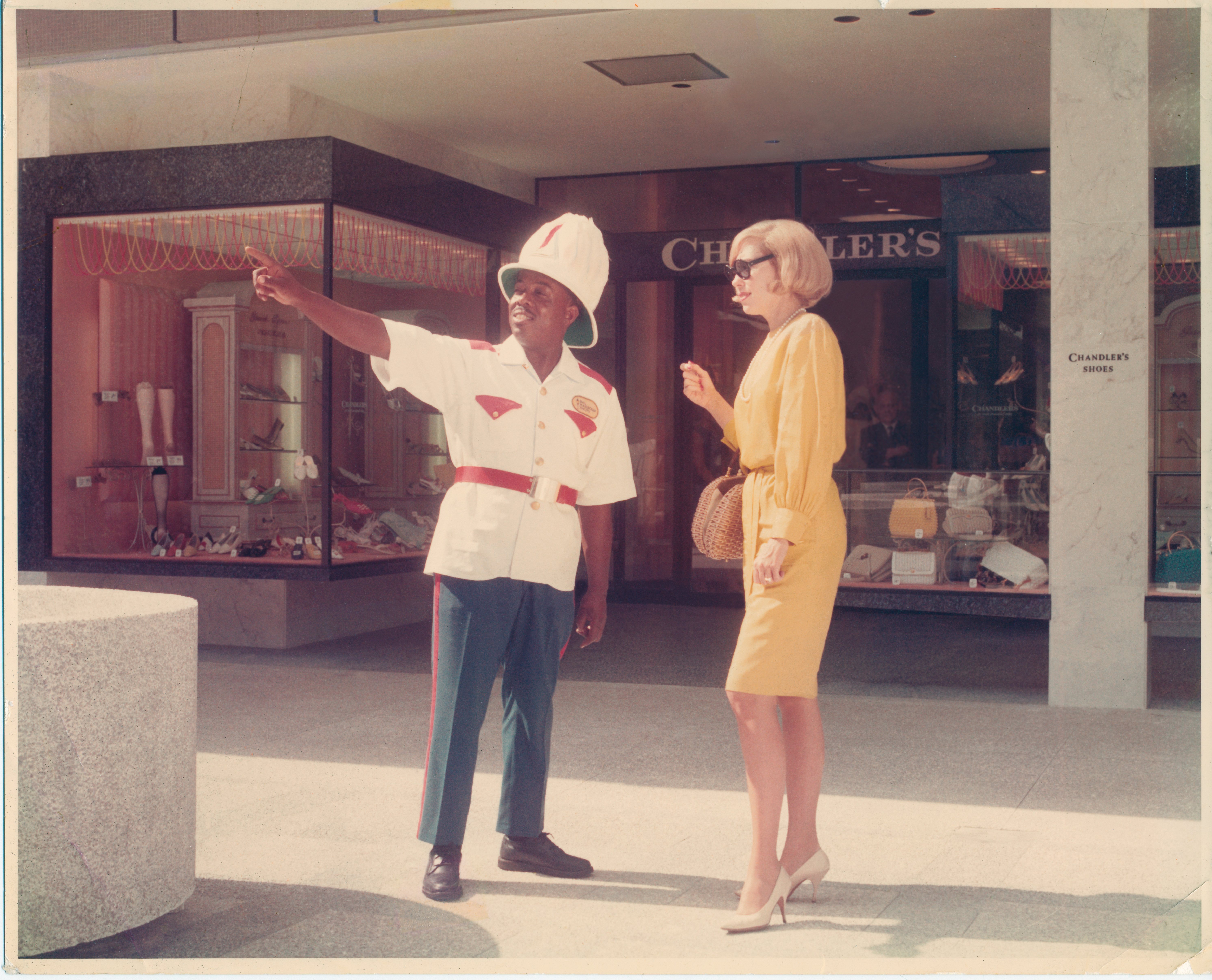 Employee working as "Frazier" the iconic Bal Harbour Shops attendant dressed in a white and red Bahamian police uniform providing guidance to a shopper.