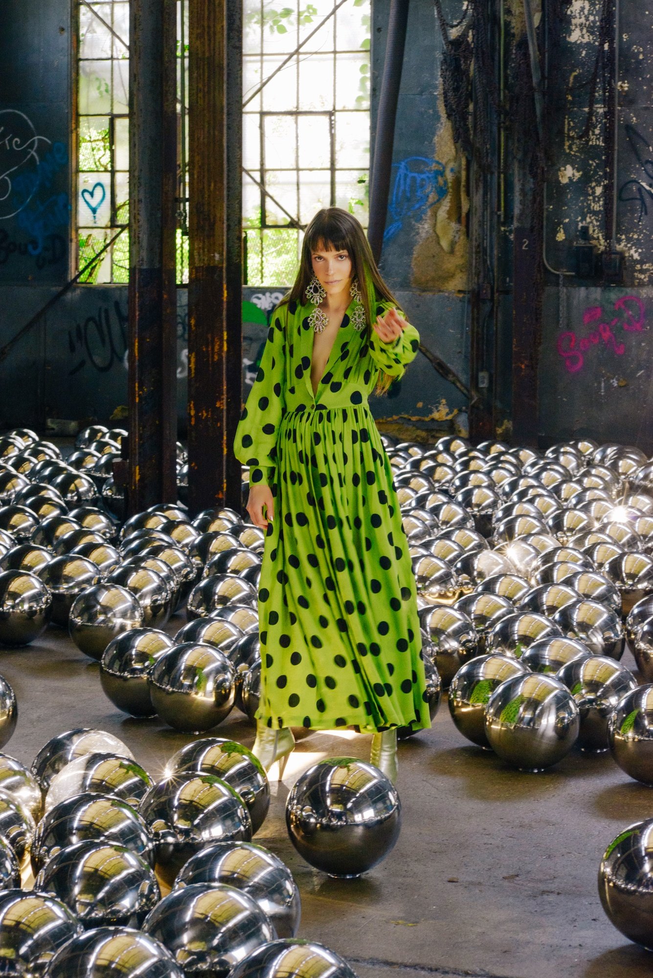 Pari Ehsan wearing a Todd Oldham dress with black polka dots and green satin amongst Yayoi Kusama's Narcissus Garden installation in New York last summer.