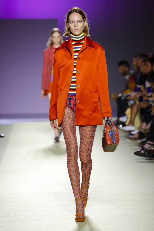 Versace Spring 2019 runway look, fire orange silk overcoat with striped turtleneck and patterned stockings