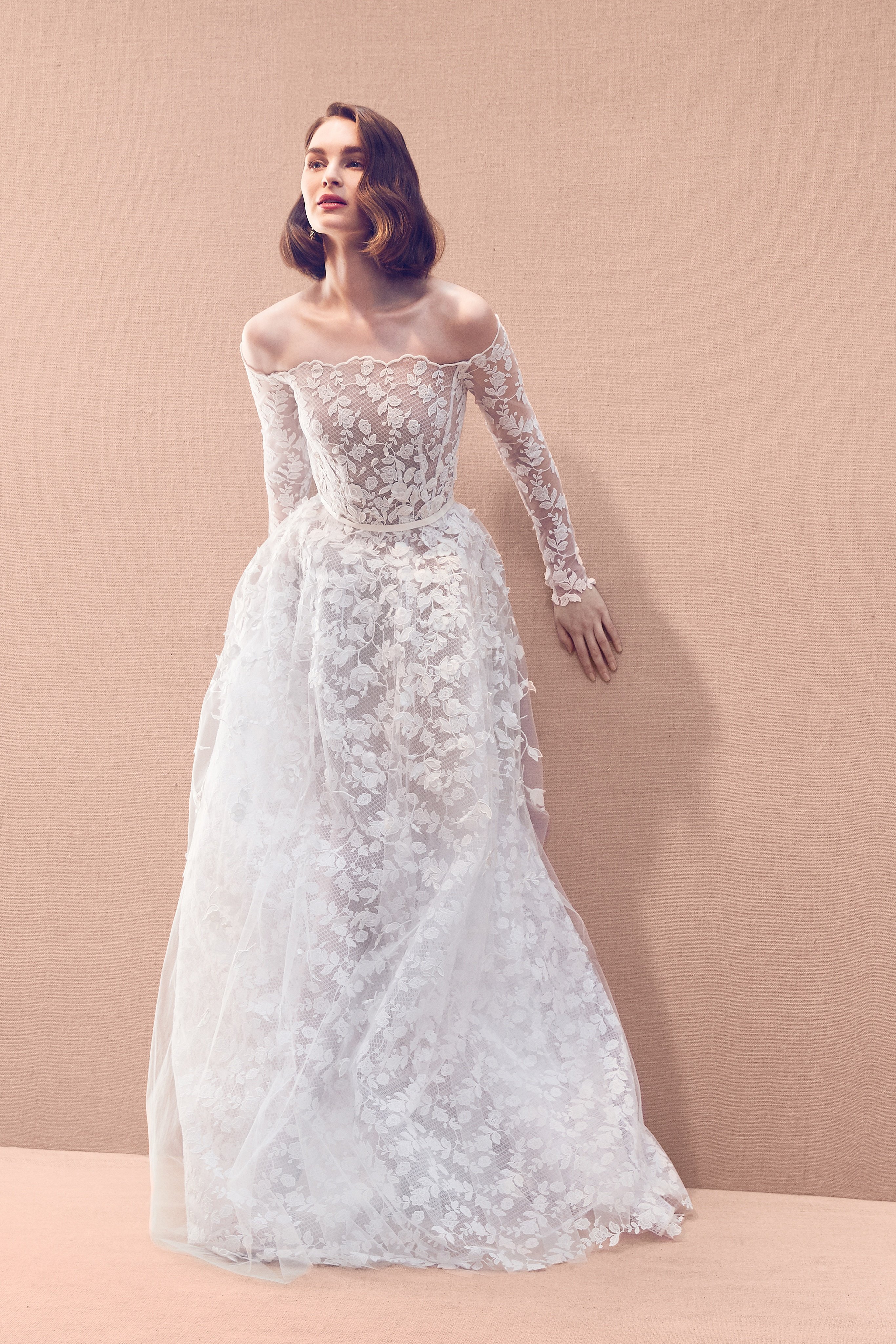 Long sleeve allover floral lace embroidered lace gown with tulle overskirt featuring organza appliqués attached on to a base of ari embroidery threadwork for a 3-D effect, totaling 80 hours of work to complete.