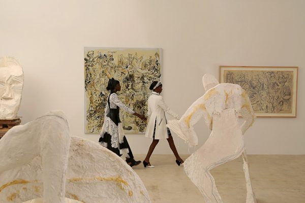 On Janica: Alexander McQueen leather and lace dress and leather boots with buckle. On Eftagine: Chanel white tweed coat, black and white tweed skirt, pumps and hair accessories. Artwork by Thomas Houseago (foreground) and George Condo. Photographed by Pablo Costanzo.