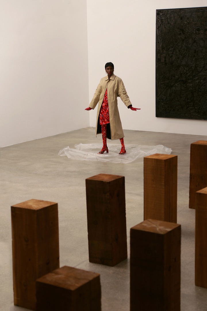 Balenciaga khaki oversized coat, red Eiffel Tower-print dress and leggings, open toed mules and monogrammed jewelry. Artwork by Carl Andre (foreground) and Rashid Johnson.