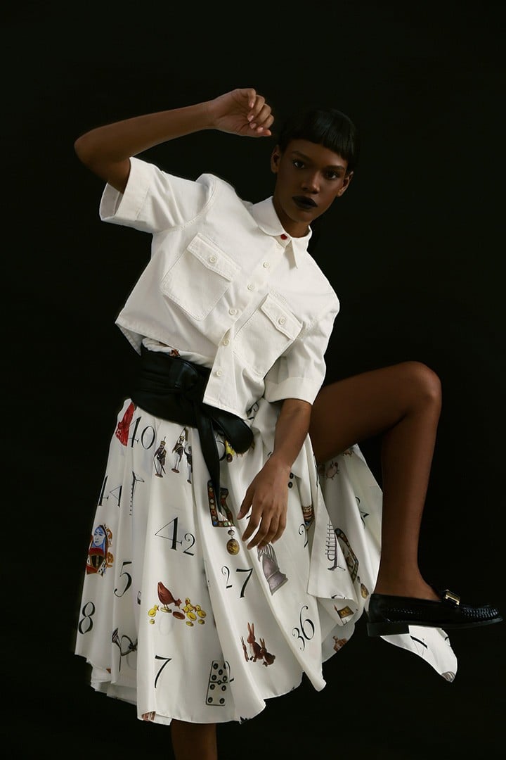 Heron Preston white short-sleeve button-up, available at The Webster. Monse silk pleated platform skirt, available at Saks Fifth Avenue. Prada black leather loafers with gold detail.