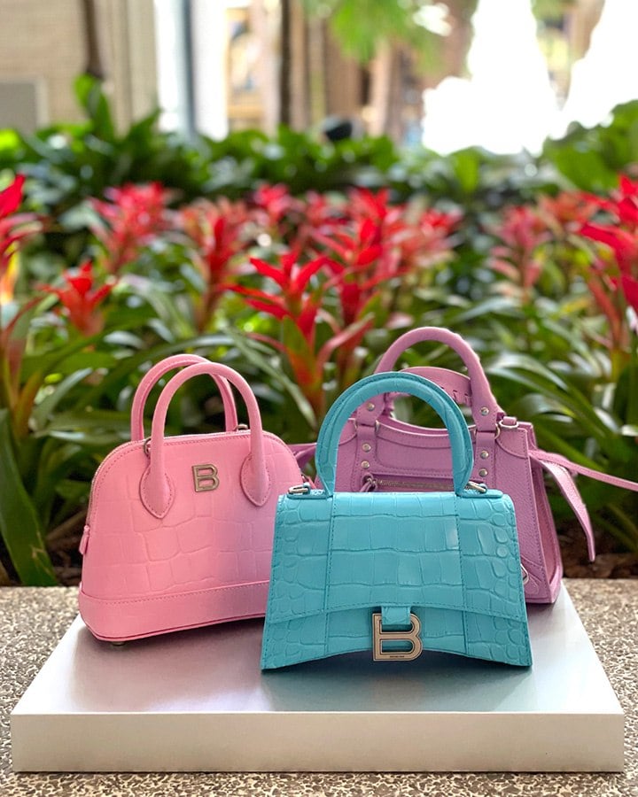 Balenciaga Hourglass turquoise glossy croc-embossed leather mini bag, Balenciaga Ville Supple Small Top Handle Bag in pink croc-embossed leather and Balenciaga Mini Neo-Classic City Leather Top Handle in lilac.