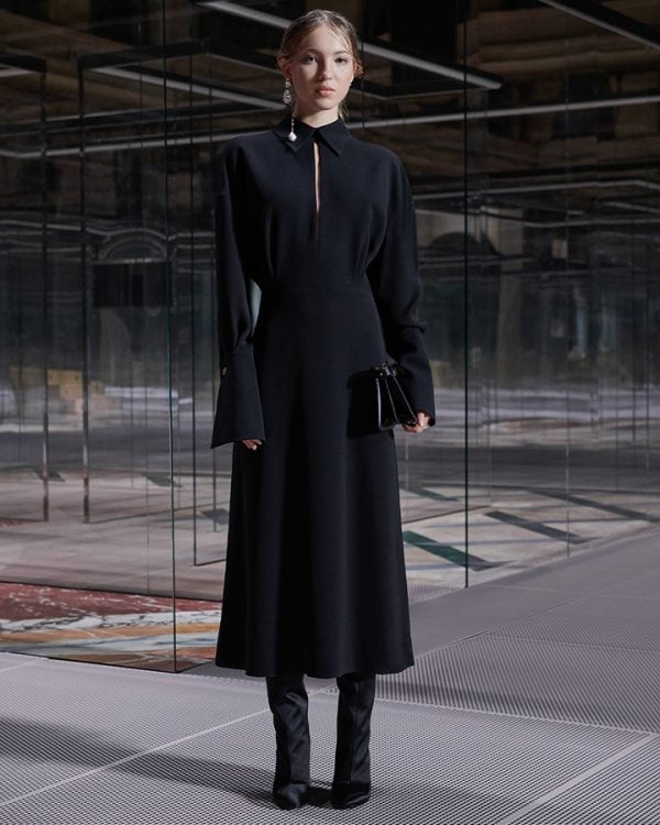 Lili Moss wears a flare-sleeved silk blouse and black skirt paired with black satin boots and black leather Peekaboo bag.