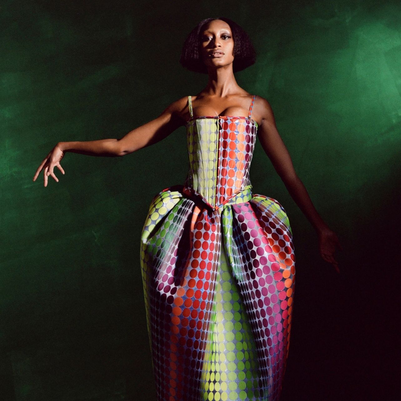 Woman poses wearing a structured dress with a multicolored dot pattern