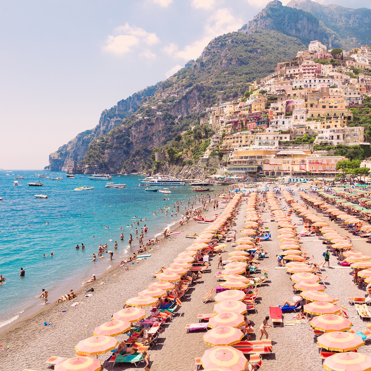 Photo of Positano Beach Vista lined with multi-colored umbrellas and people wading in the water