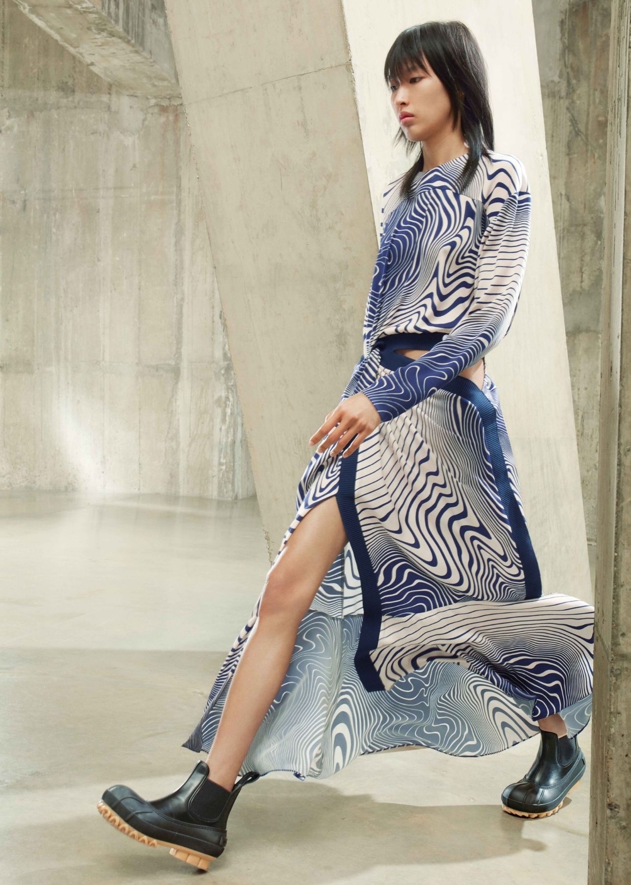 Woman walking on runway in Stella McCartney blue patterned dress and black rubber boots