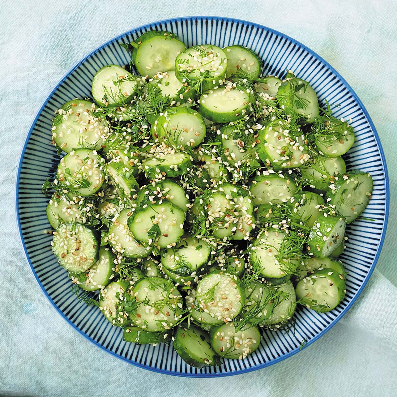 photo of a chopped cucumber salad with sesame seeds, dill and parsley