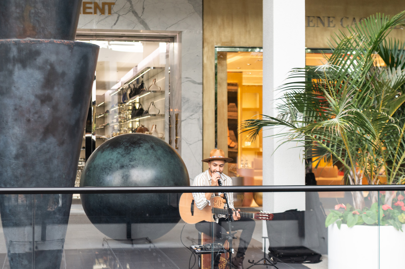 Andrade World photographed with a guitar and singing into a microphone in the sculpture garden