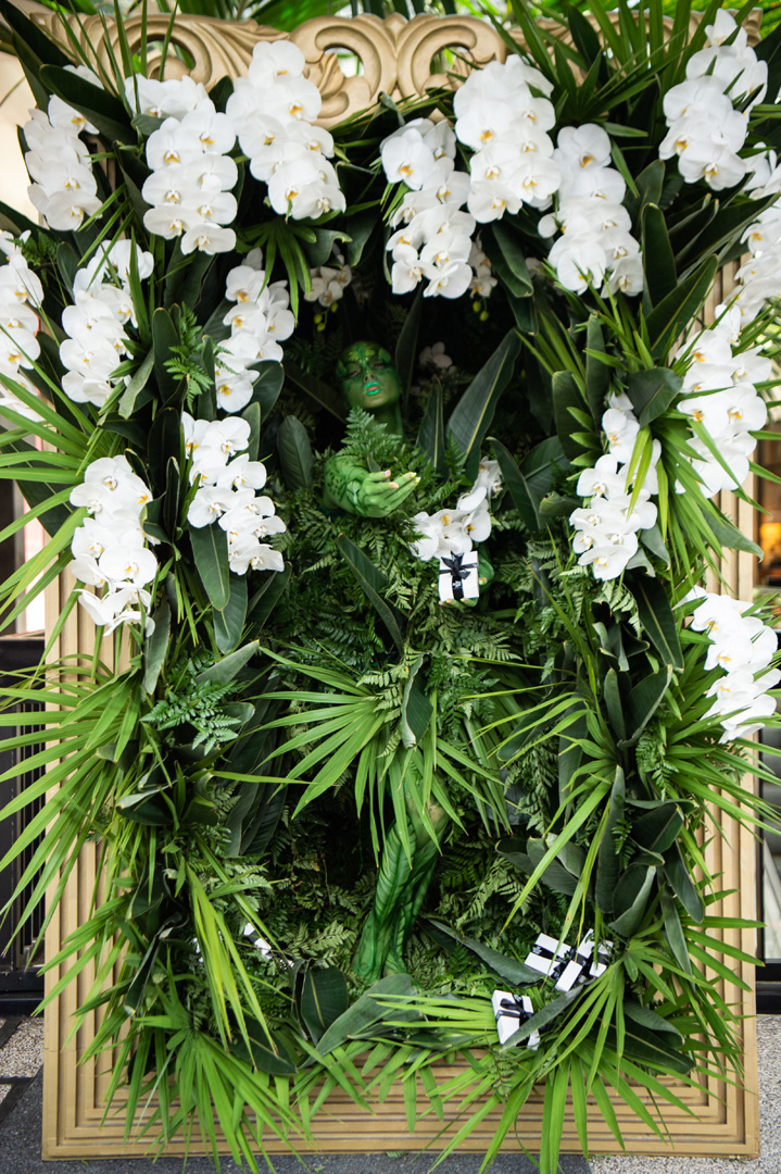 Woman dressed in camouflage surrounded by greenery and orchids