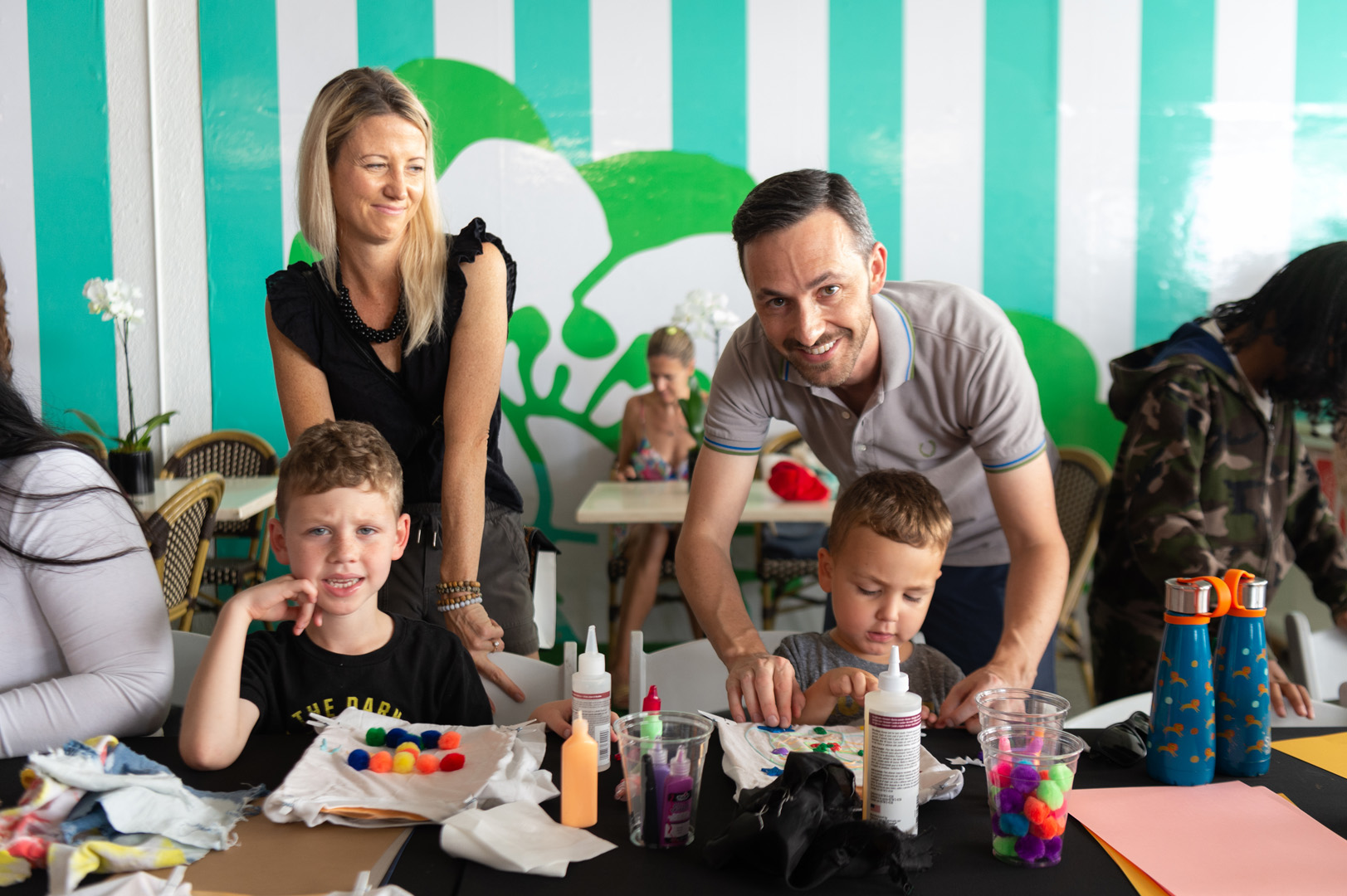 Mom and dad watching their two sons paint on t-shirts