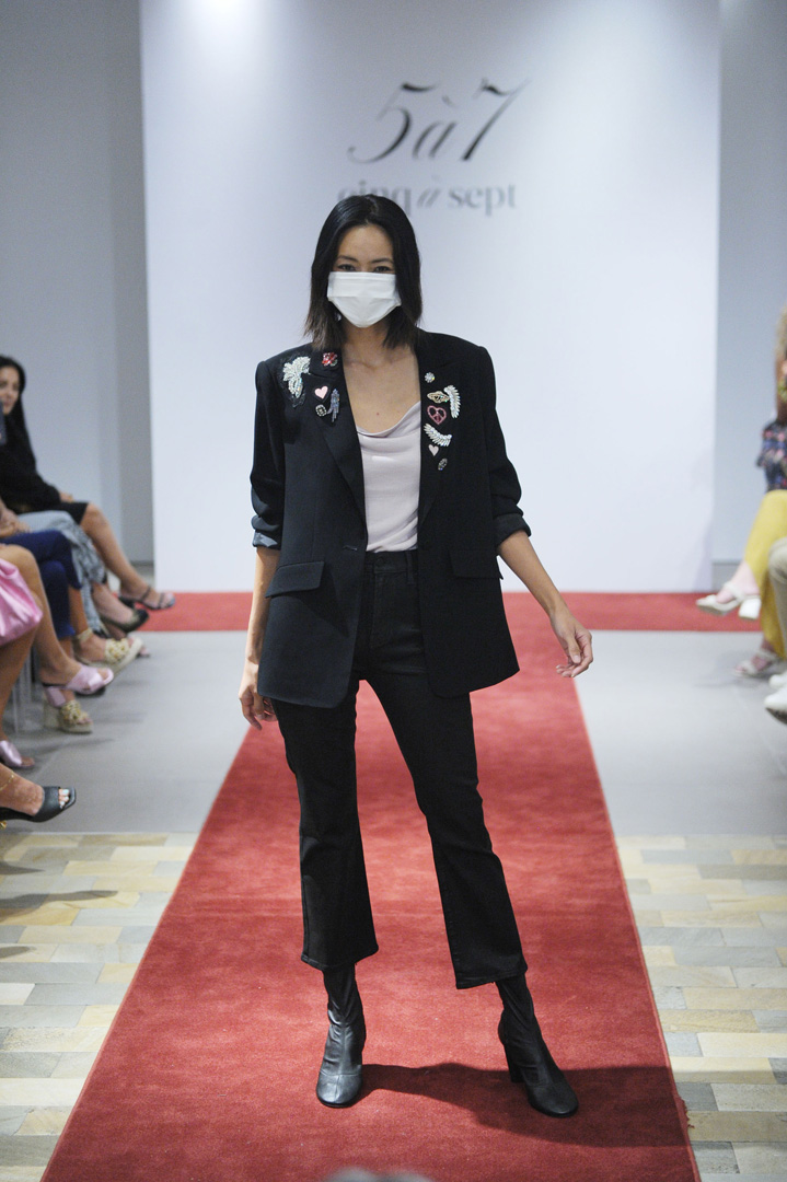 Model poses at the end of a runway in a black blazer and black pants