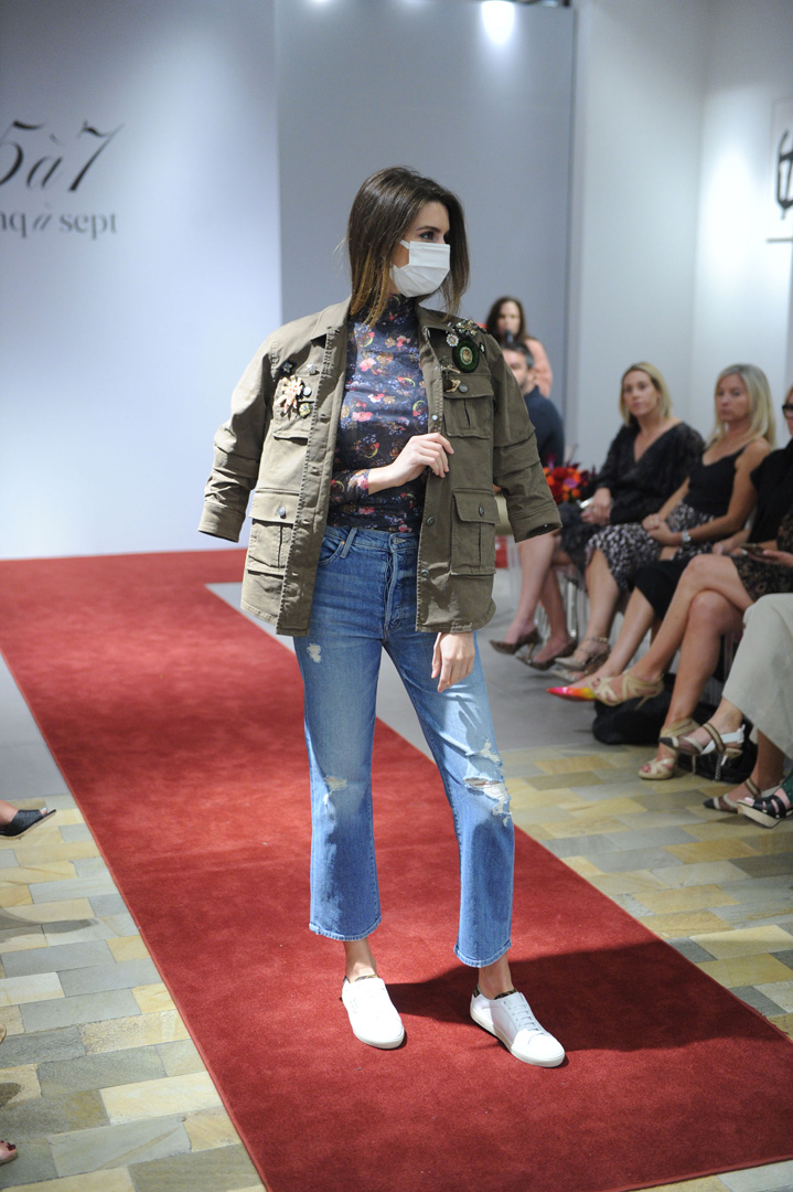 Model poses on a runway in green military jacket and denim jeans