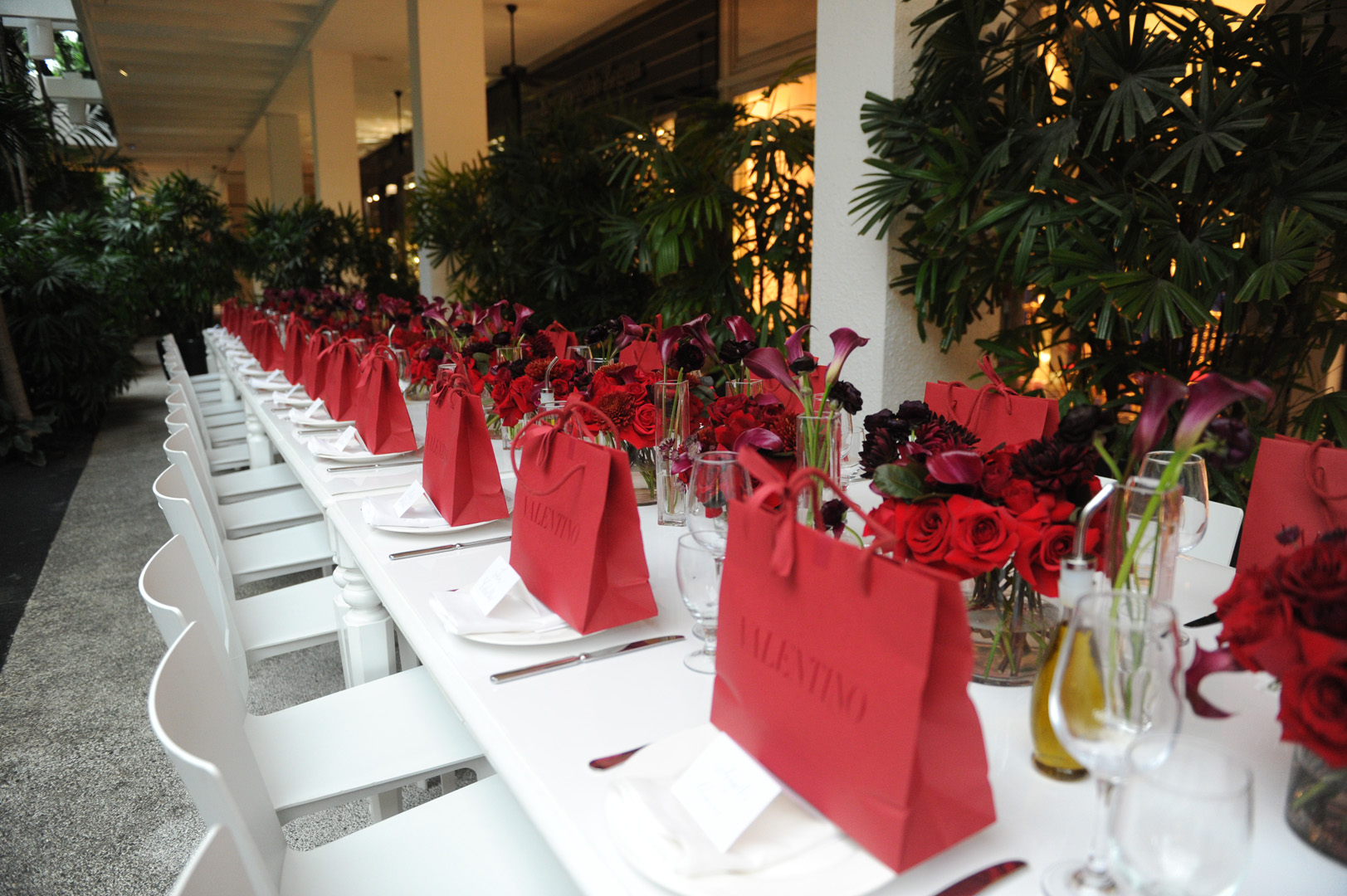 A white table set up with red roses and red valentine bags