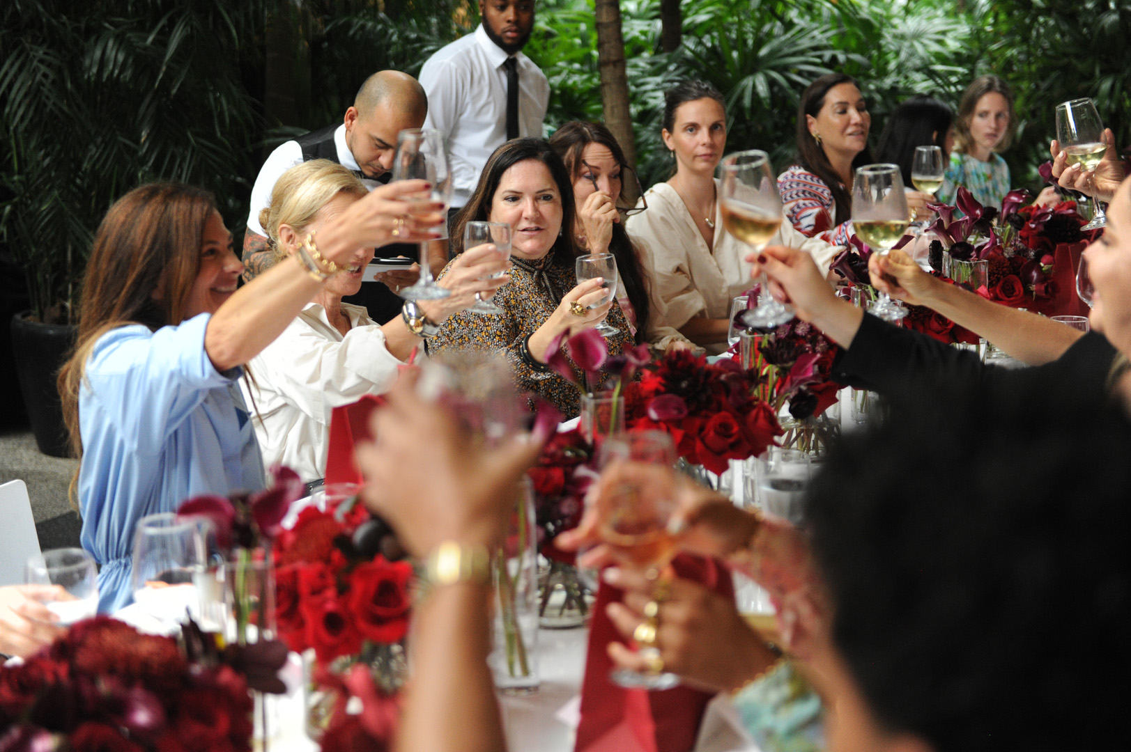 A table of woman hold up wine glasses for a toast