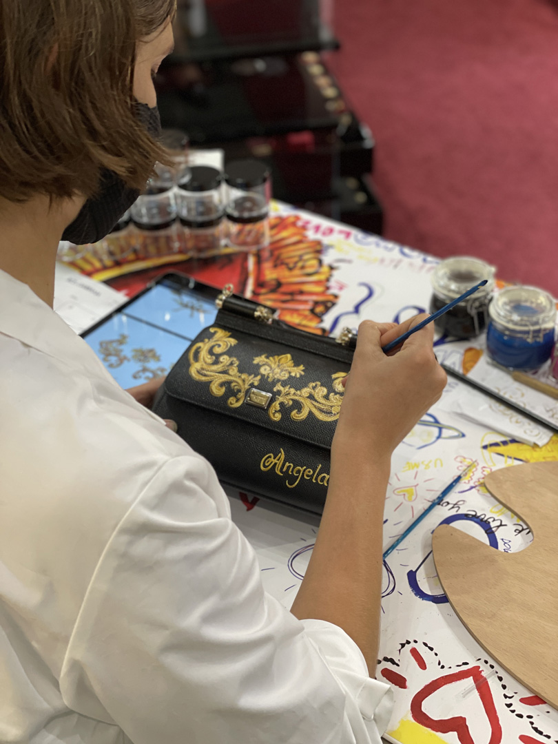 Woman paints a Dolce and Gabbana purse with a gold pattern