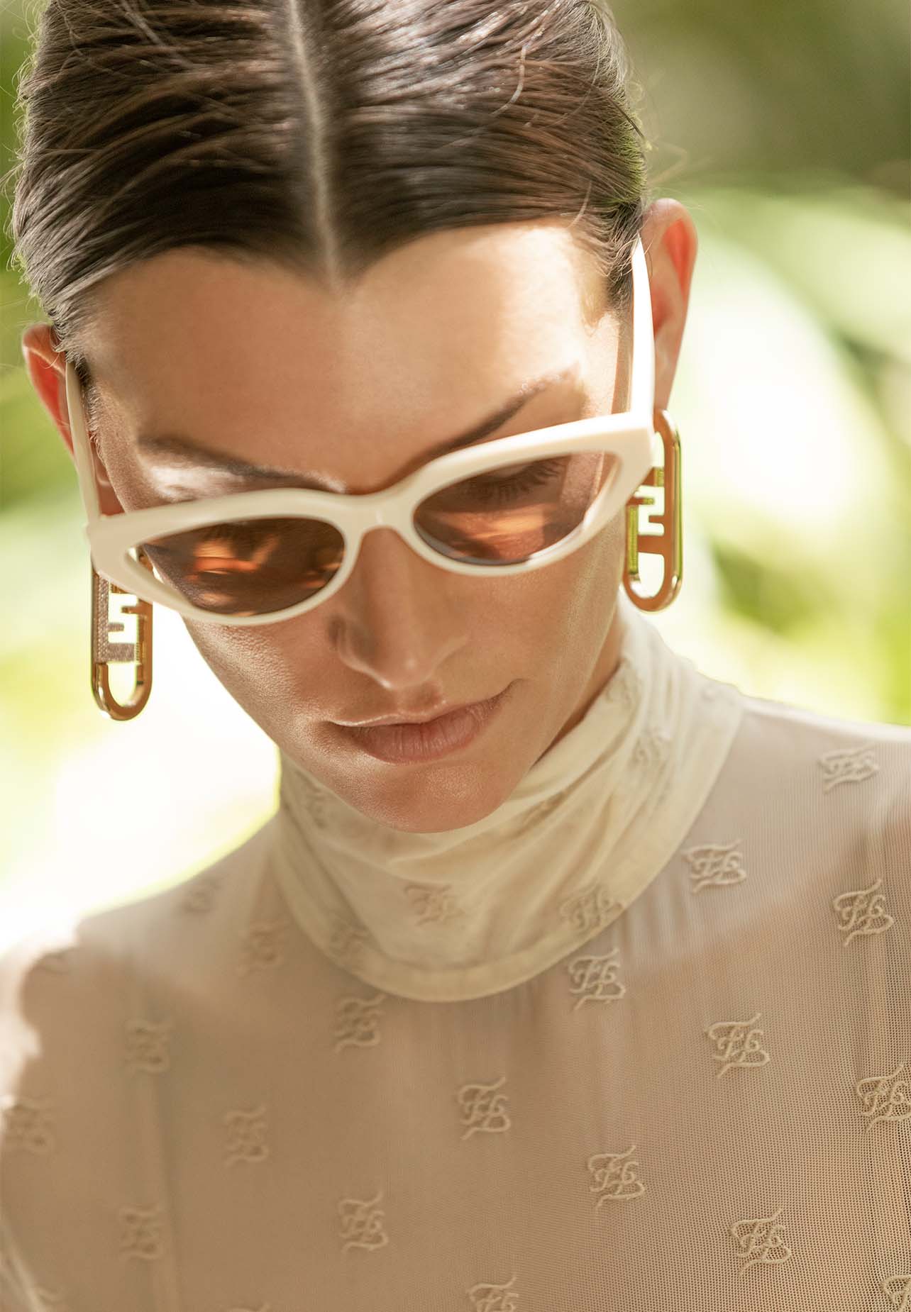 Close up shot of model wearing white sunglasses and gold drop-down earrings