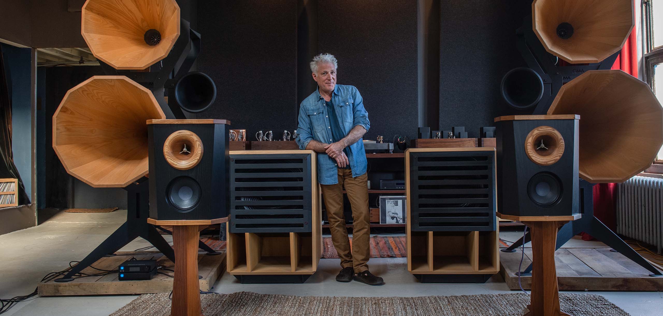 Jonathan Weiss stands in front of Oswald Mills Audio speakers