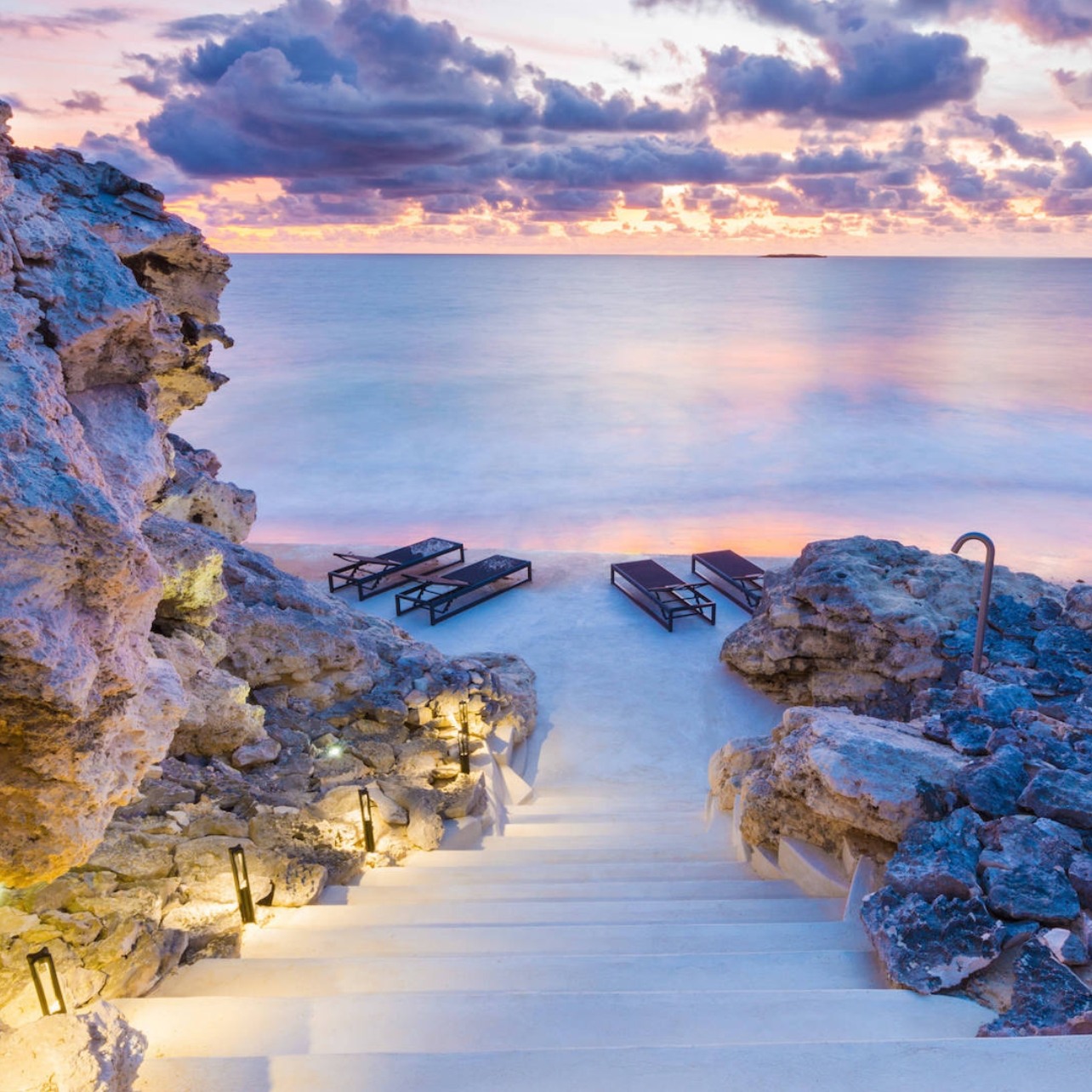 Stone staircase and framed by coastal rock, leading down to the water