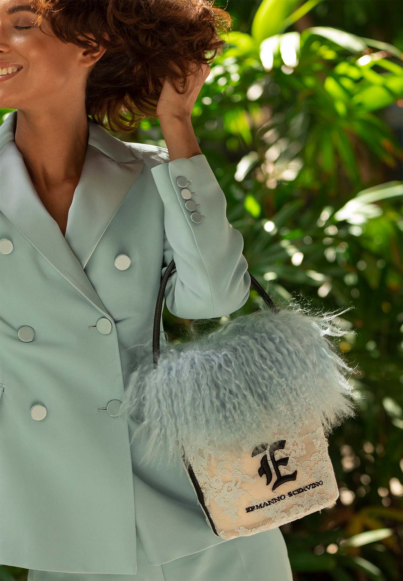 Model smiles while holding an Ermanno Scervino purse and blue suit