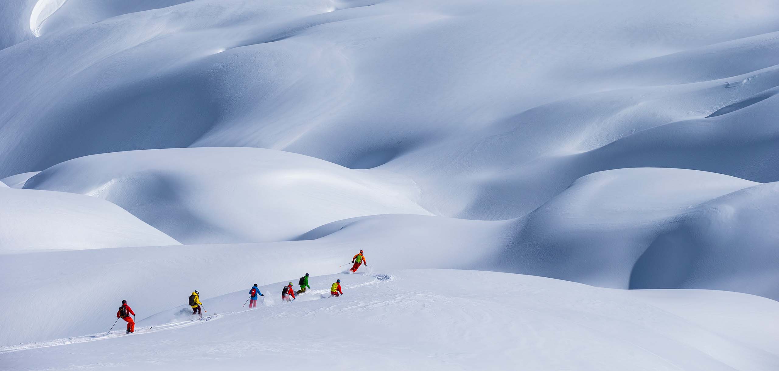 A group of heli-skiiers make their way down the mountainside