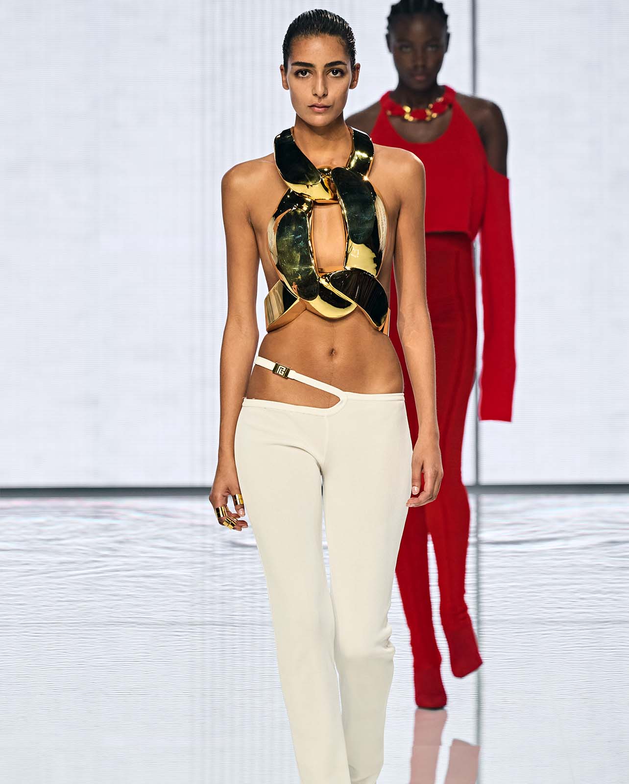 Model walking on runway in a gold chain style top