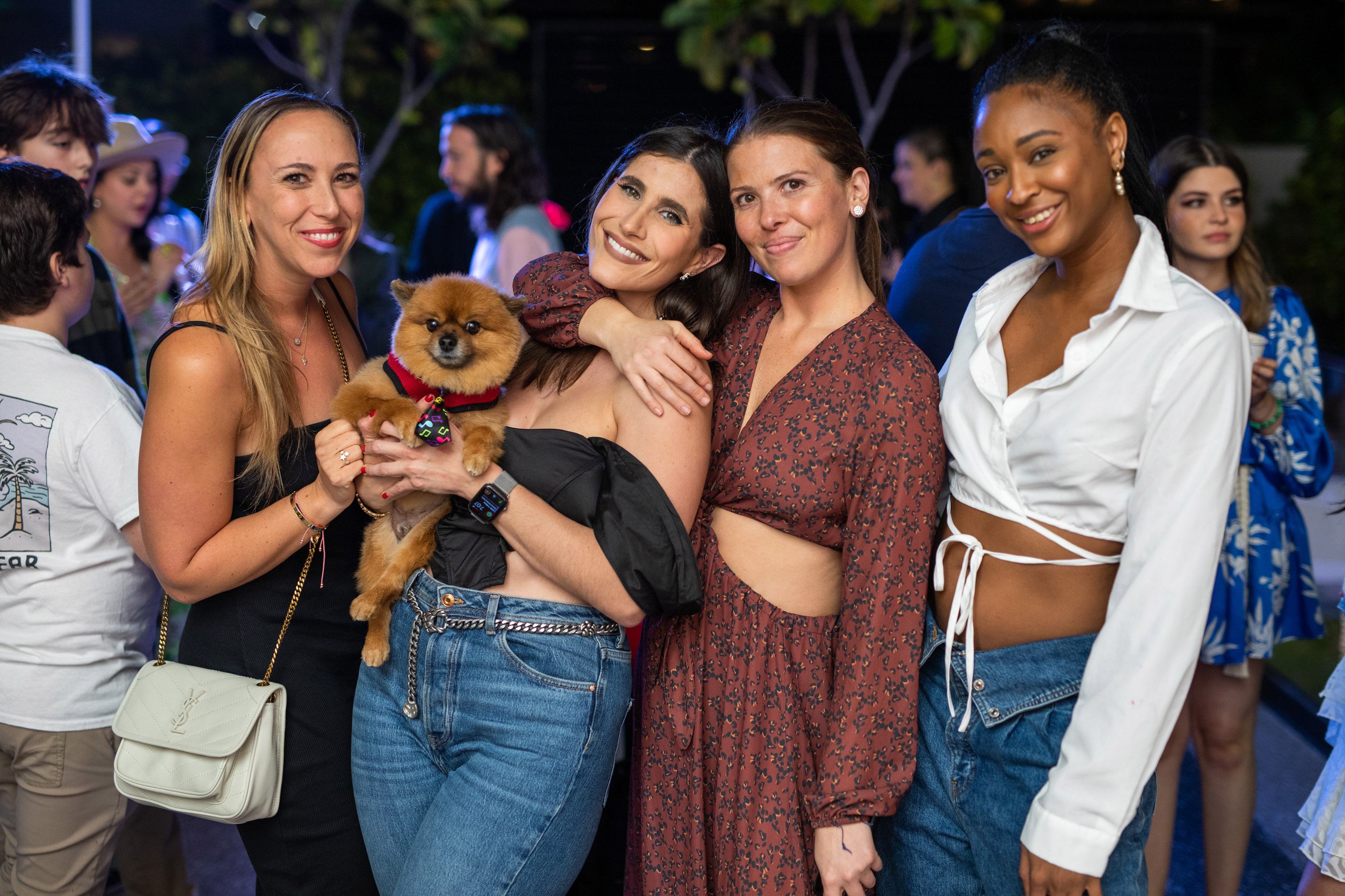 A group of women smile for a photo with a dog
