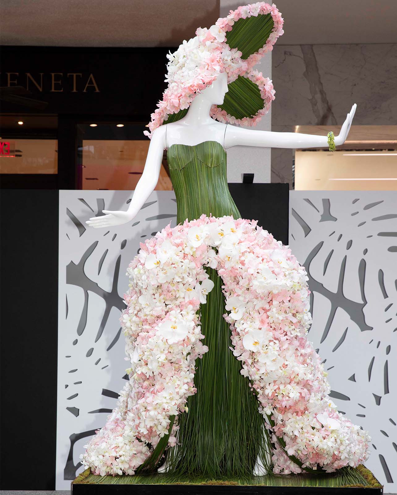 Mannequin decorated in a green palm and light pink flowers