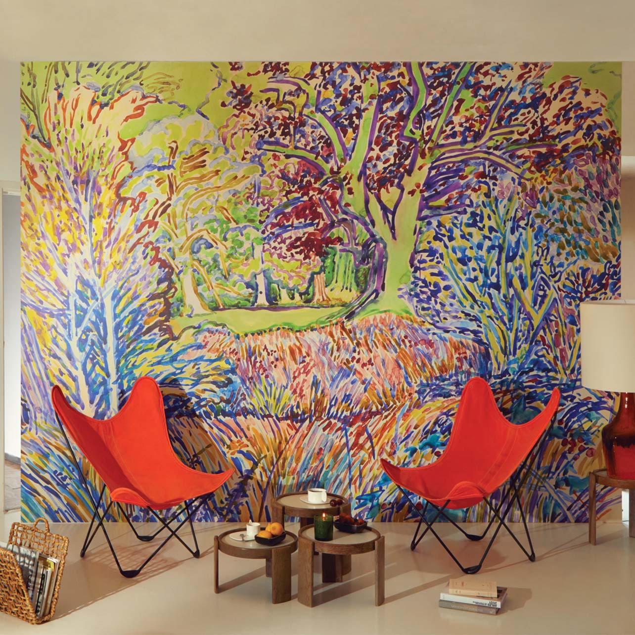 Diptyque colorful wallpaper showcased in a room with red chairs and a coffee table