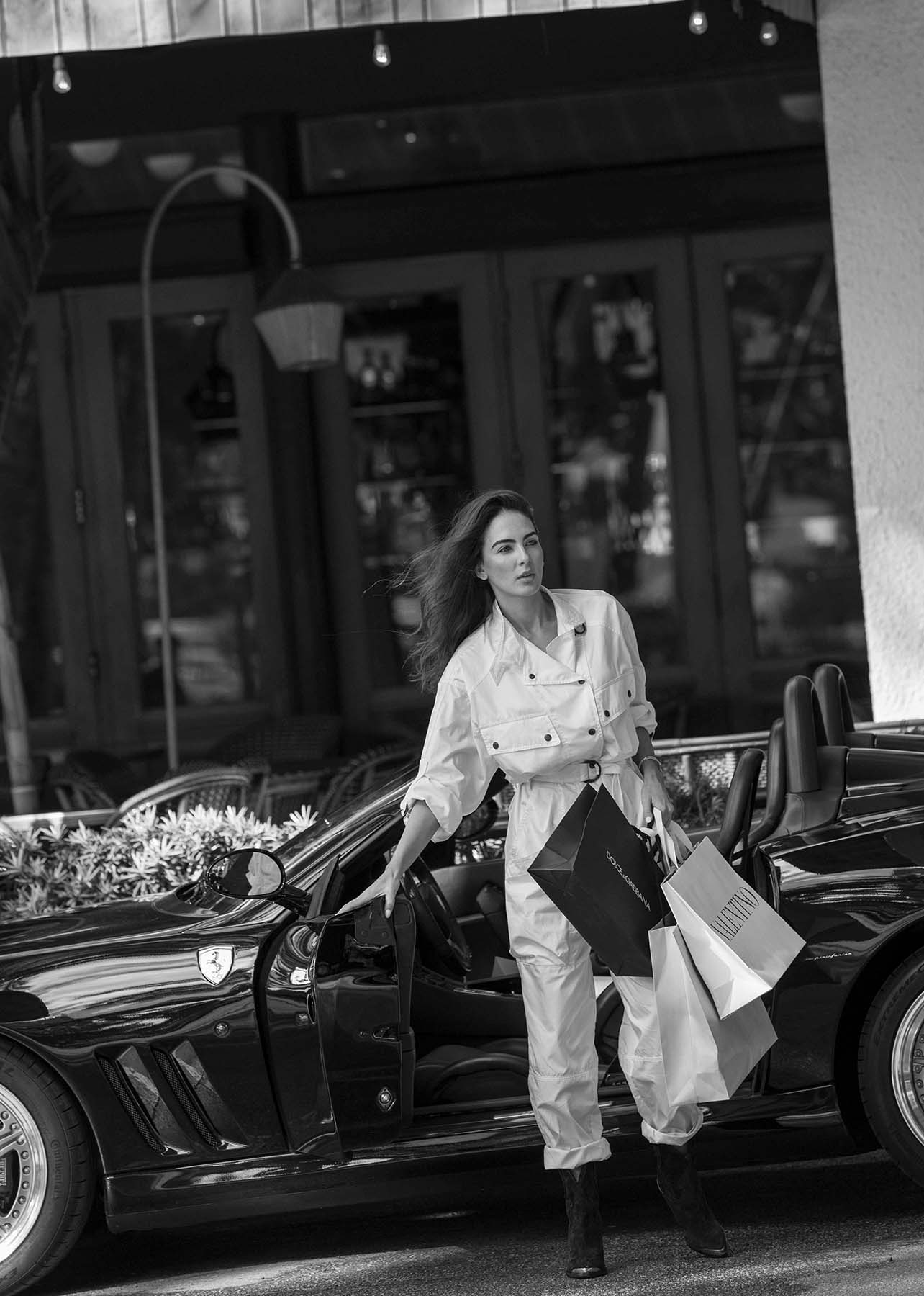 Model closes car door while holding shopping bags