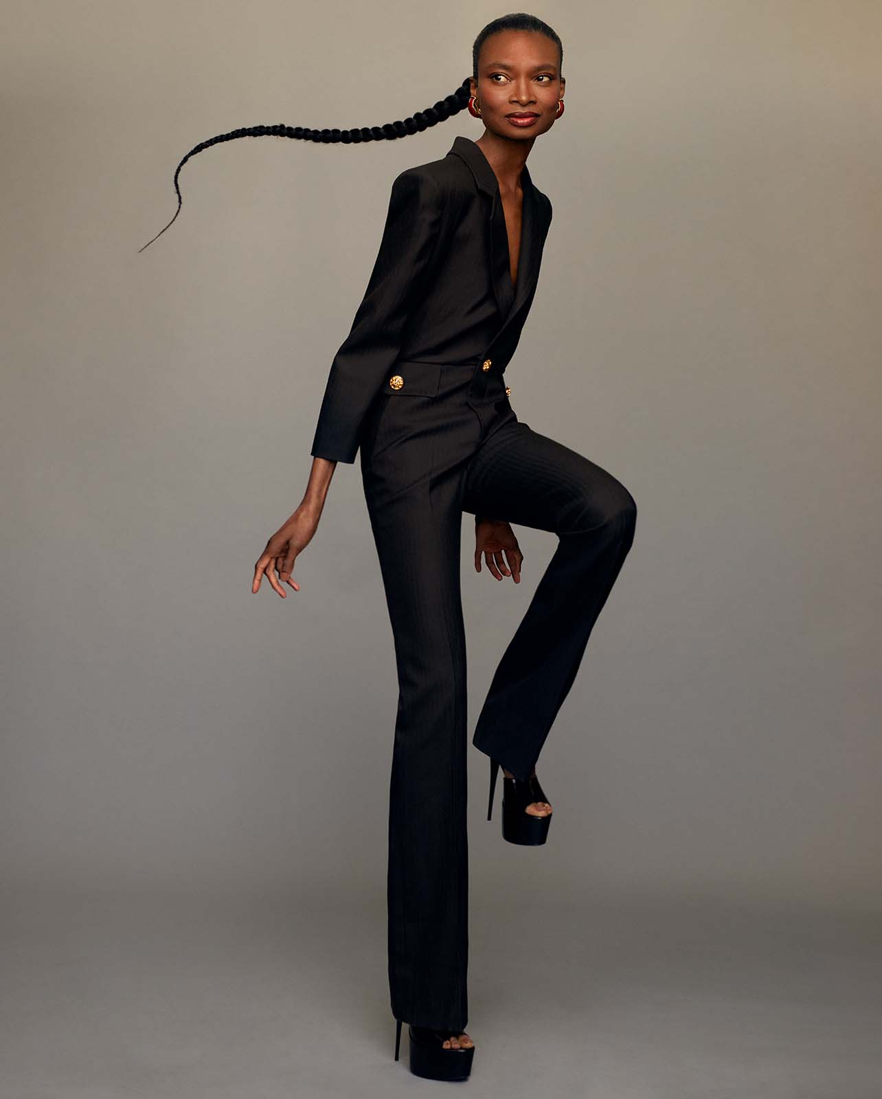 Model poses in a black suit set and black platform heels