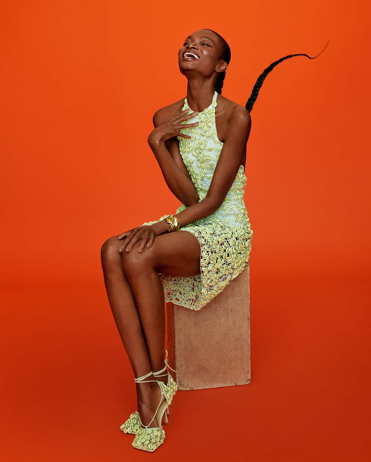 Model sits in a yellow floral dress with matching heels