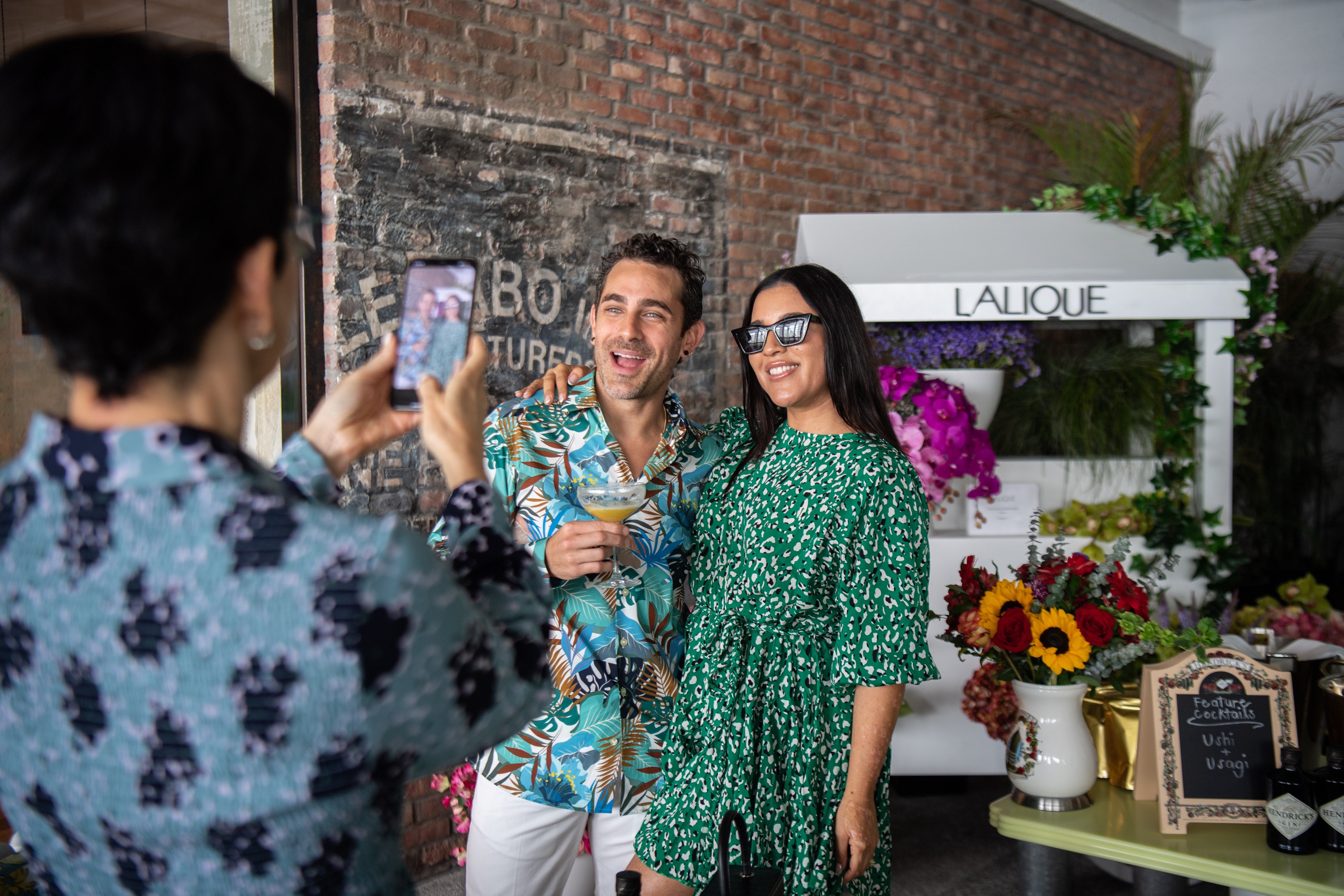 Woman snaps a photo of a man and woman smiling together