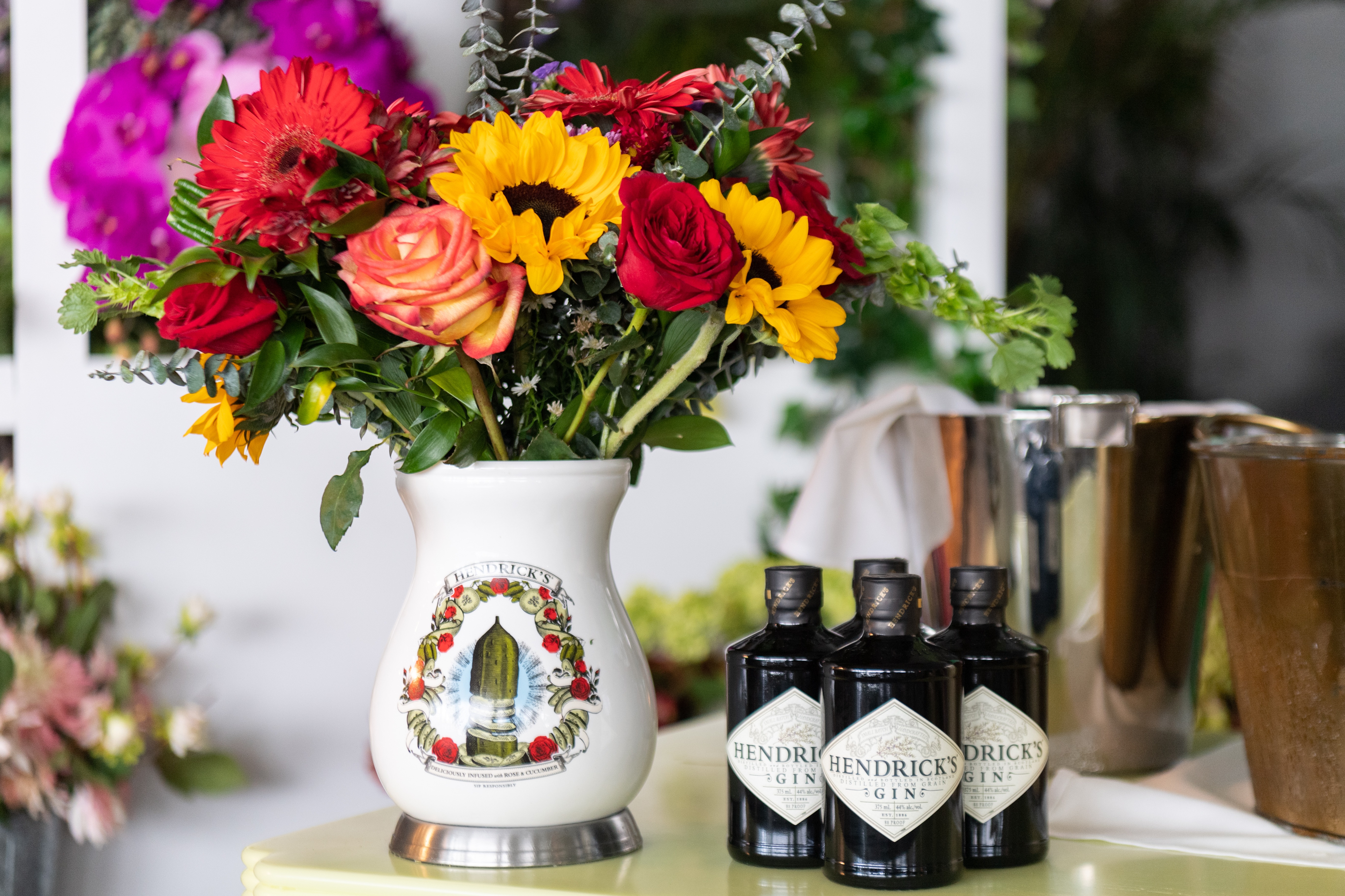 Bottles of Hendricks gin placed next to a vase of flowers
