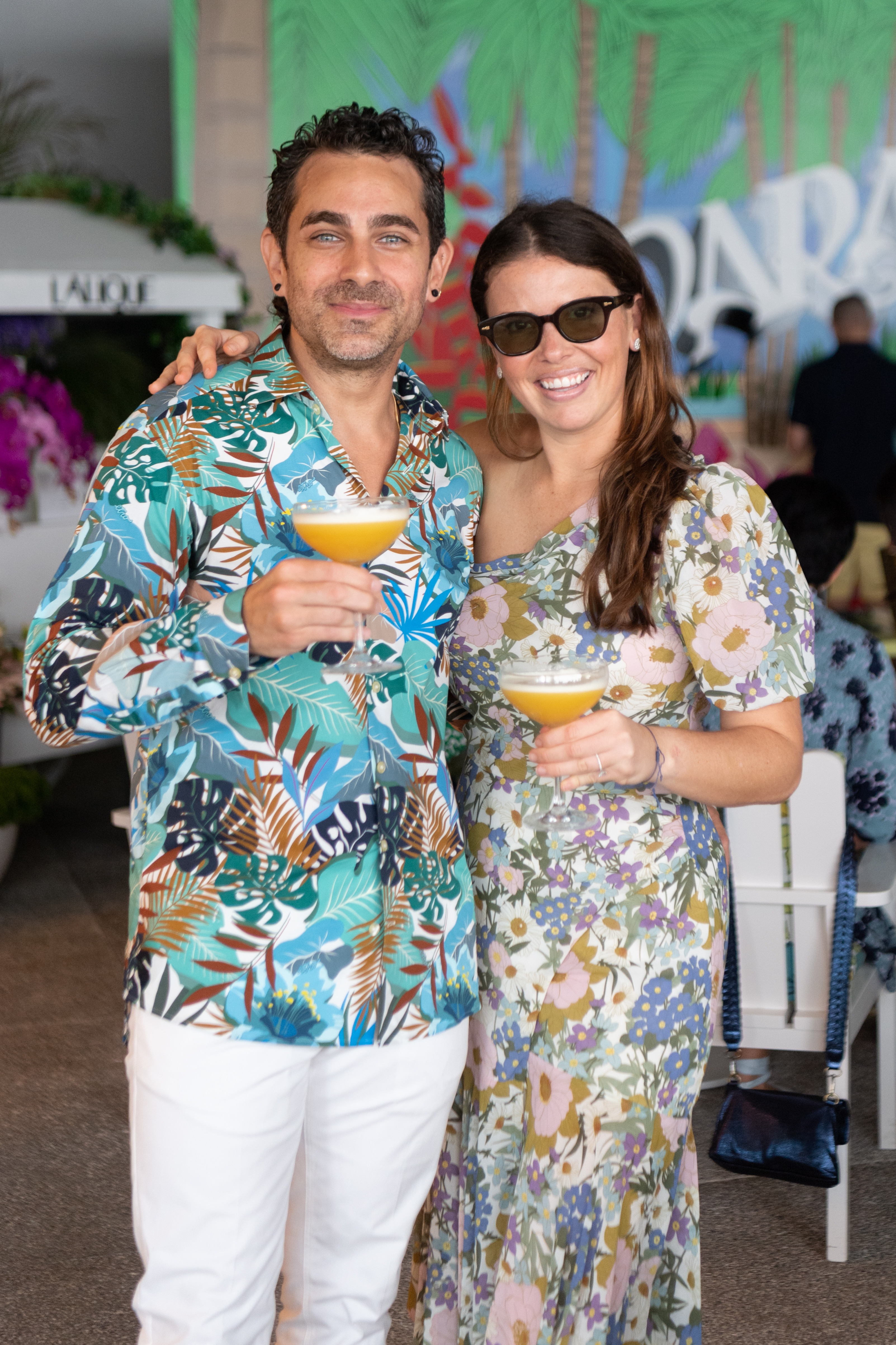 Woman and man smiling for a photo holding cocktails