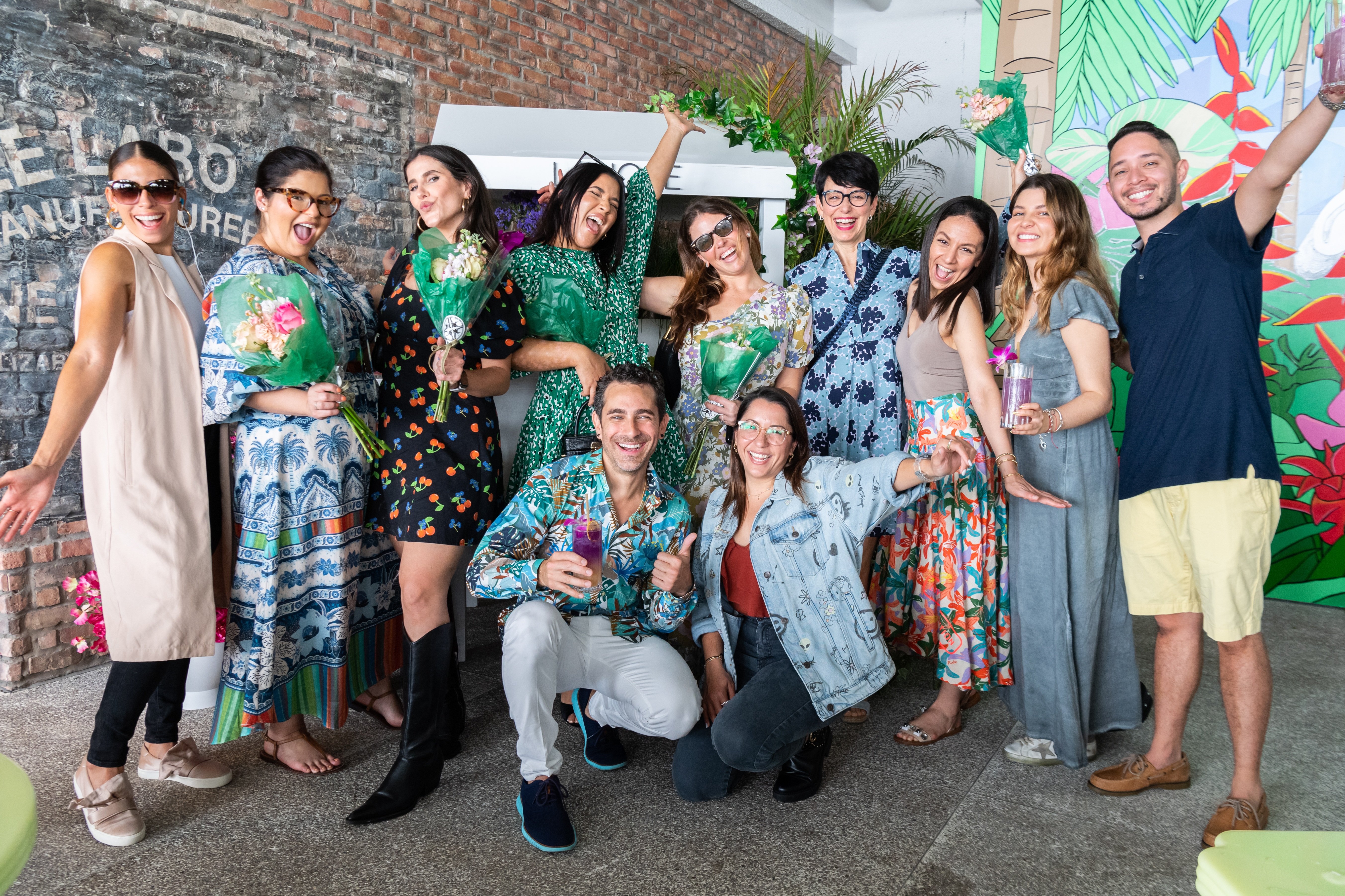 Group of party attendees smile for a photo holding flower bouquets