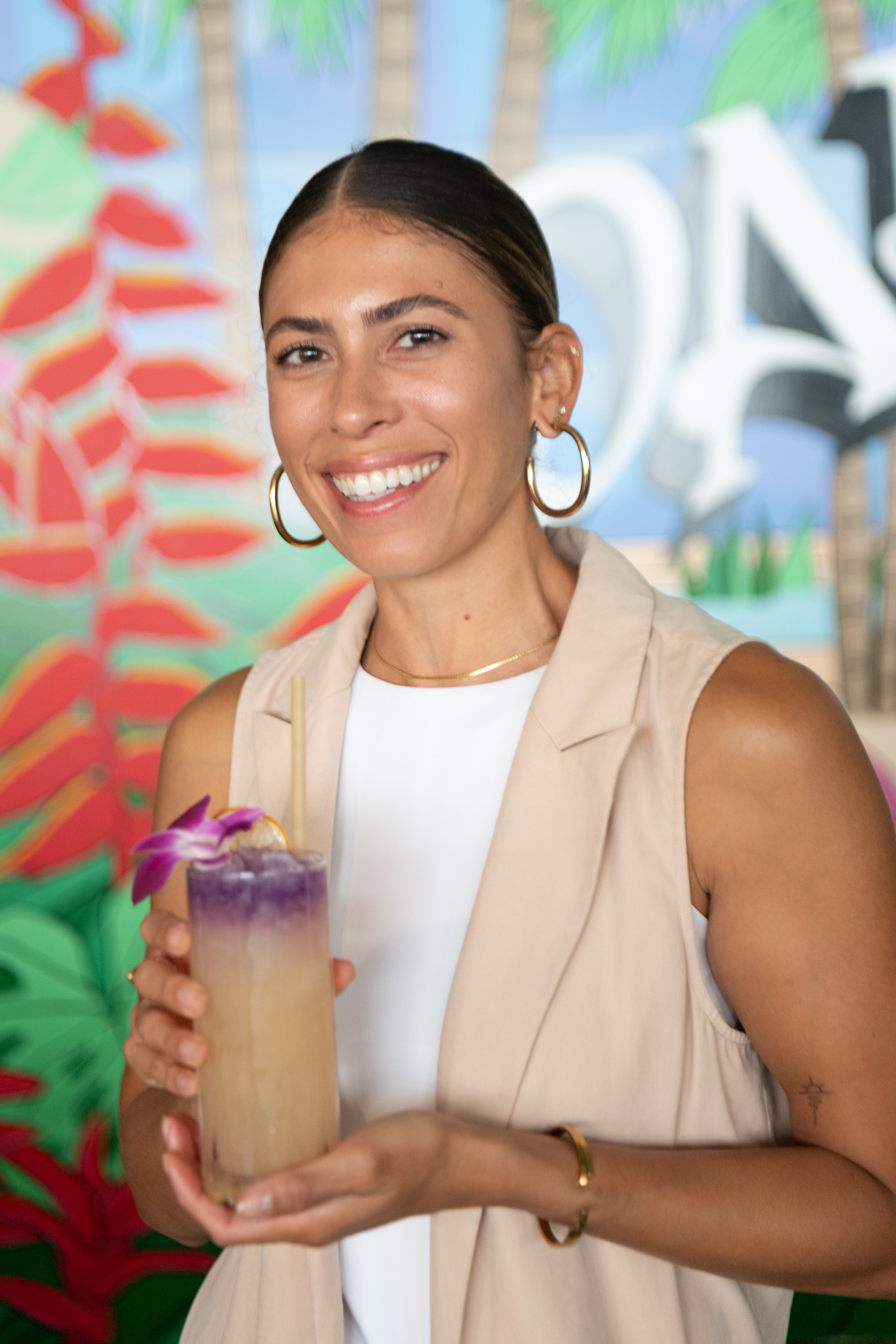 Woman smiles for a photo holding a cocktail