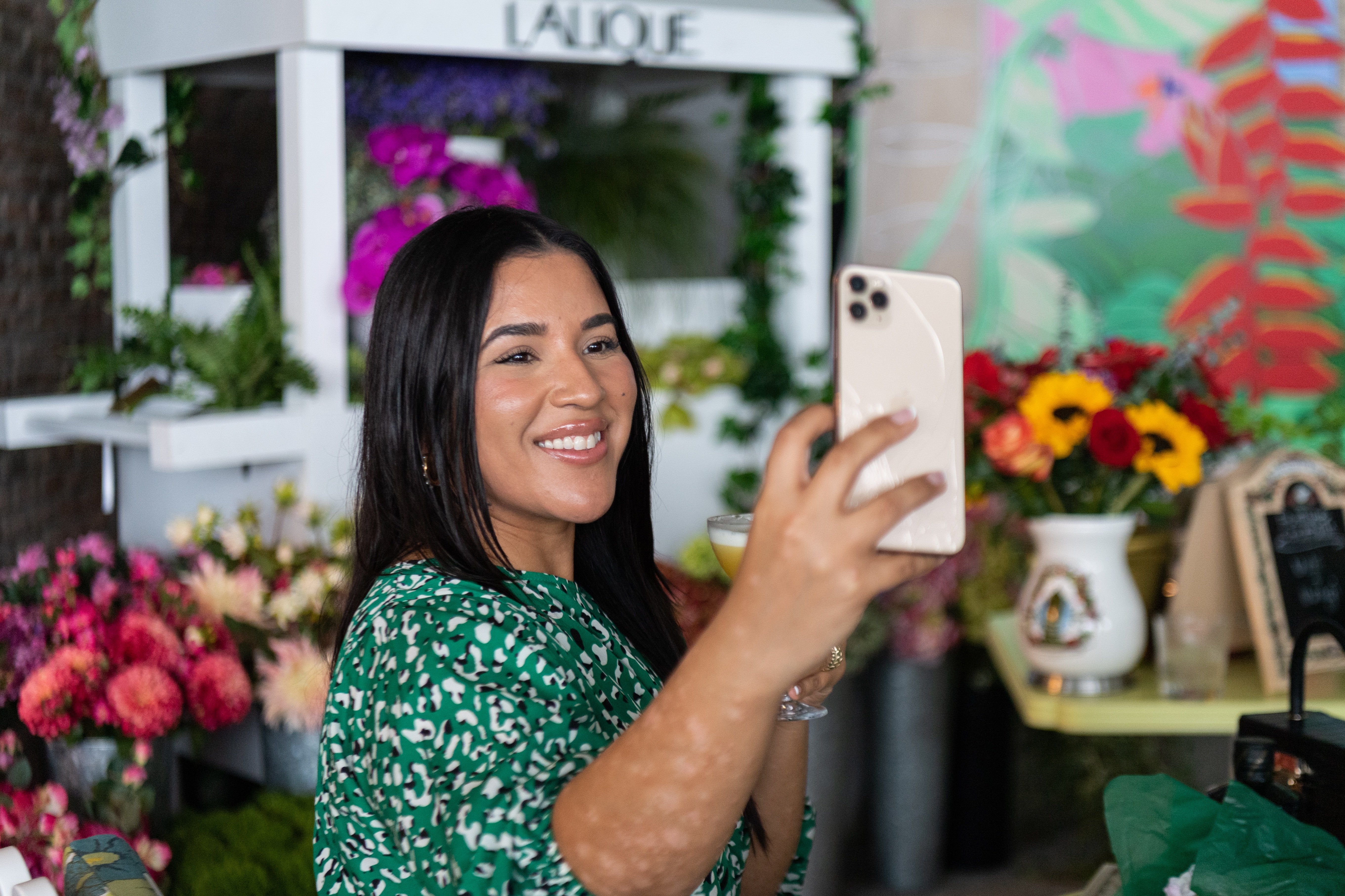 Woman holds ip a cocktail and snaps a selfie