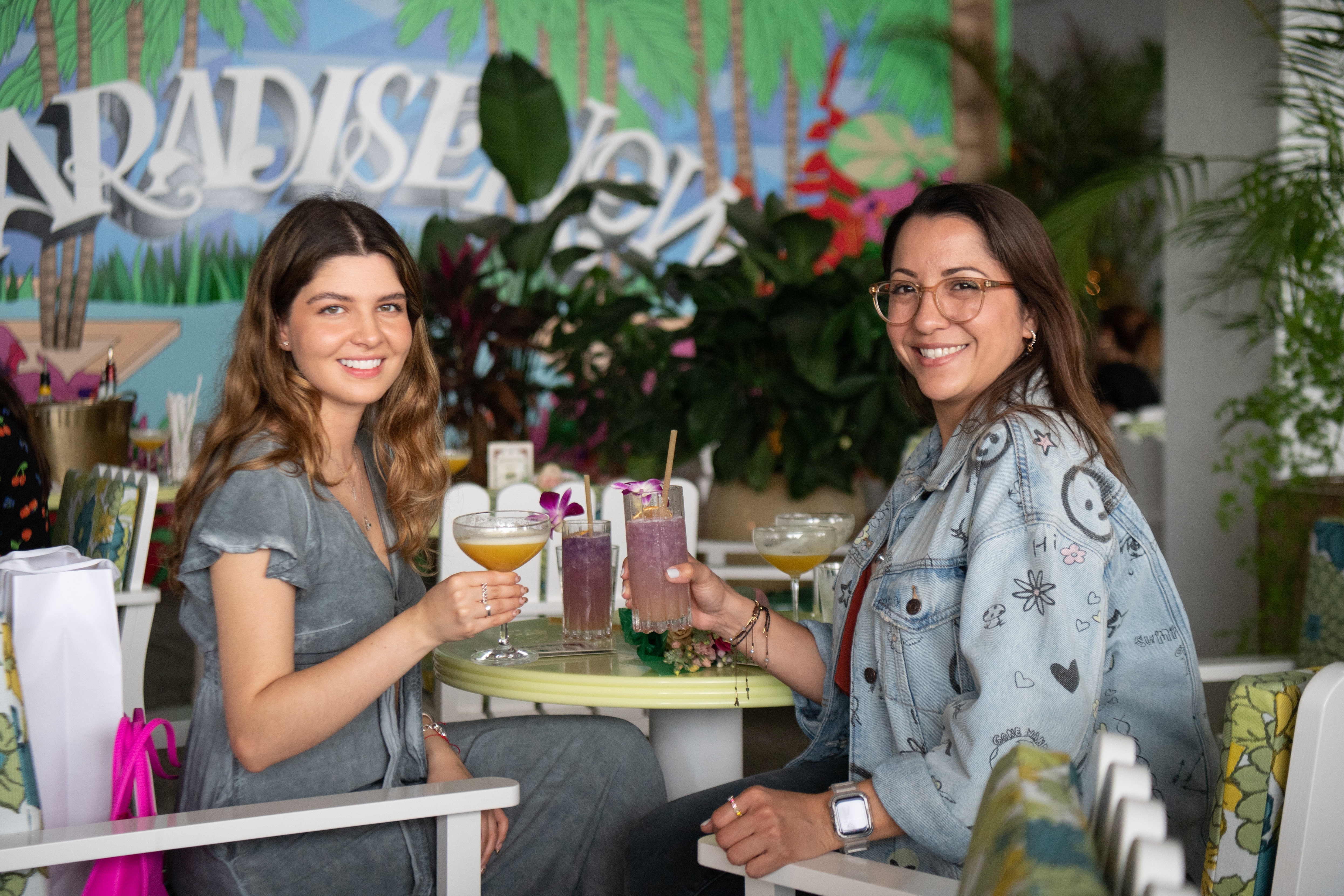 Two women hold up cocktails and smile for a photo