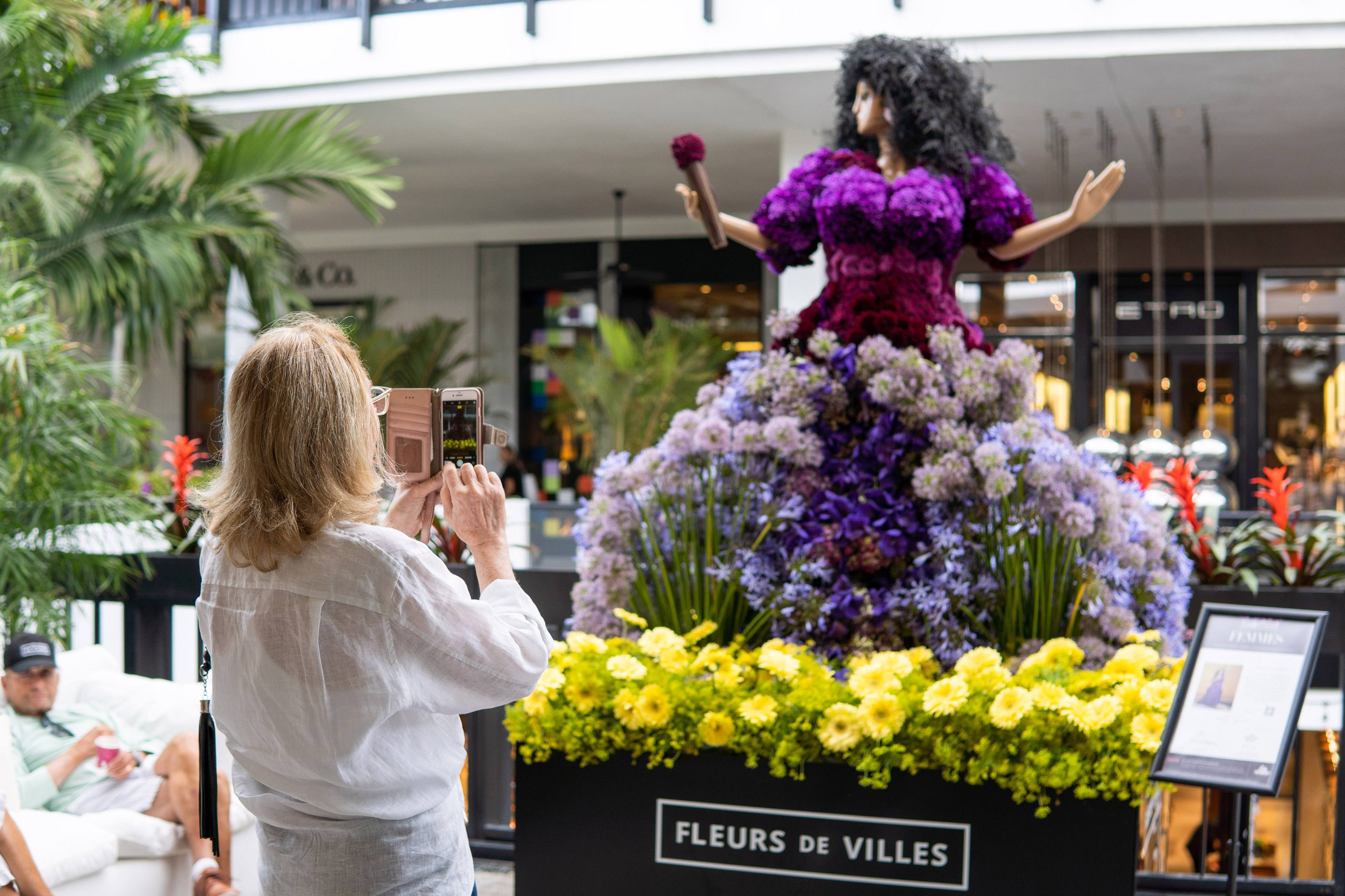 Woman takes a photo of an Oprah Winfrey inspired floral mannequin
