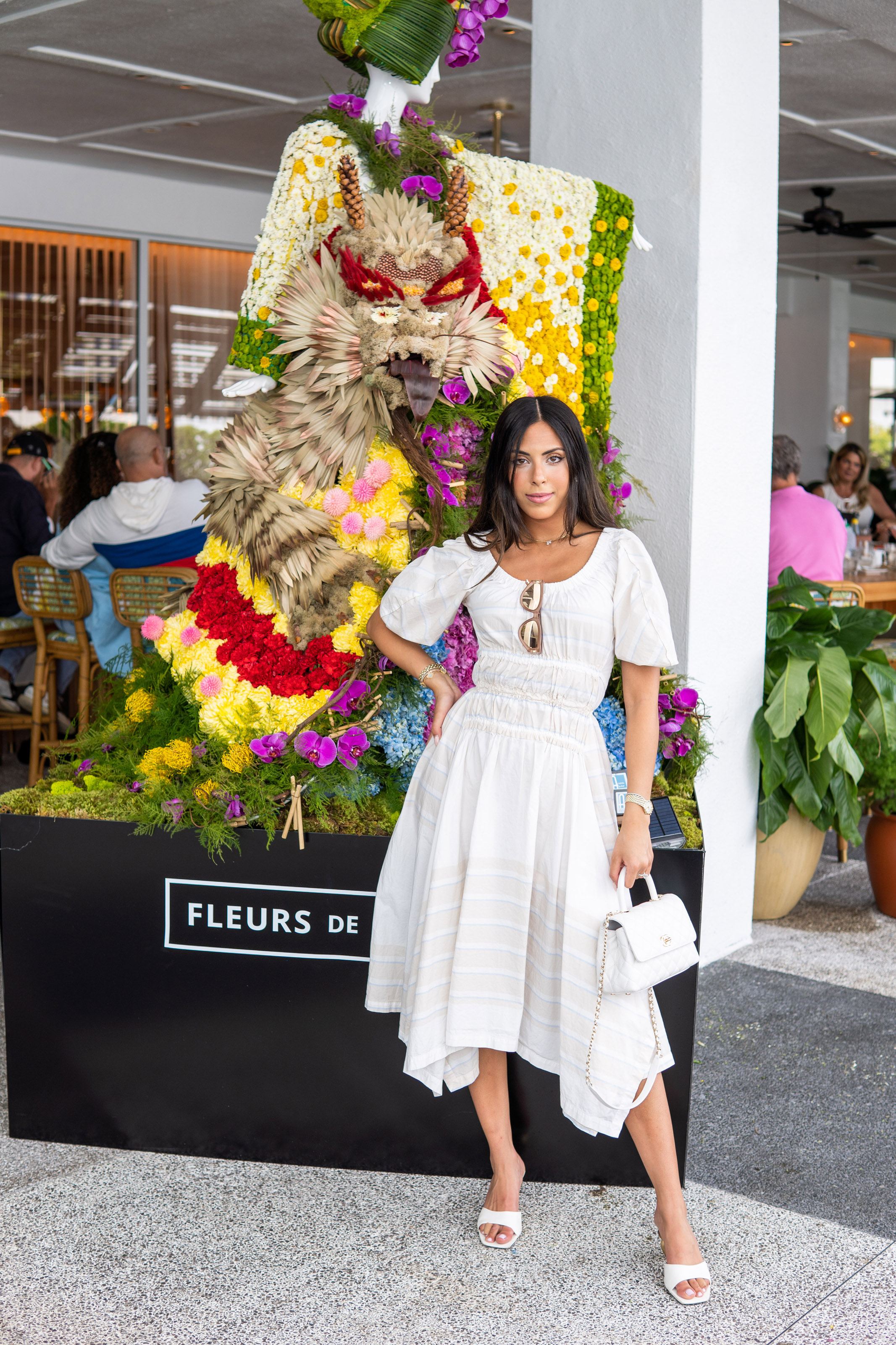 Woman poses in front of a floral mannequin