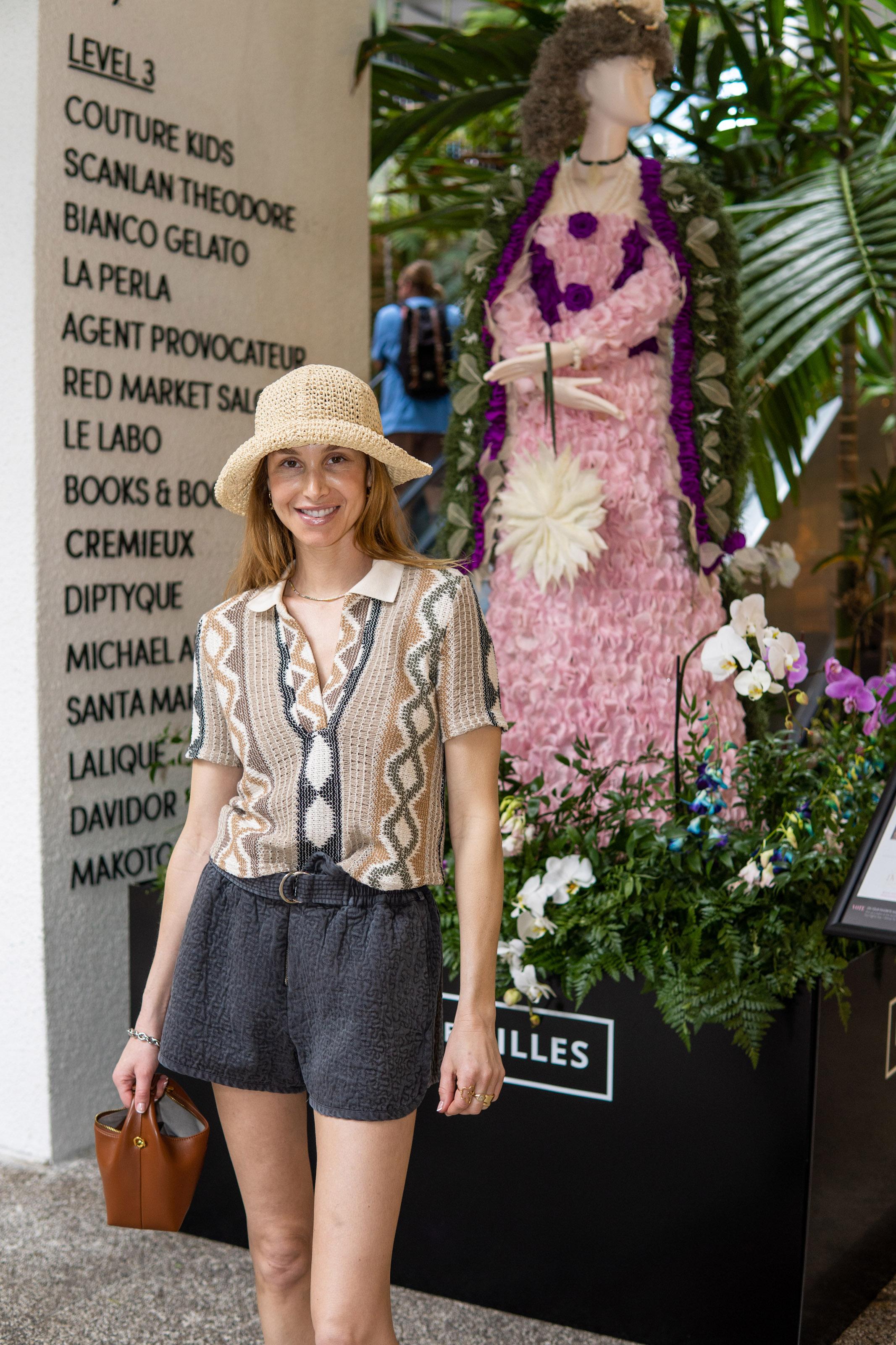 Woman smiles in front of a floral mannequin