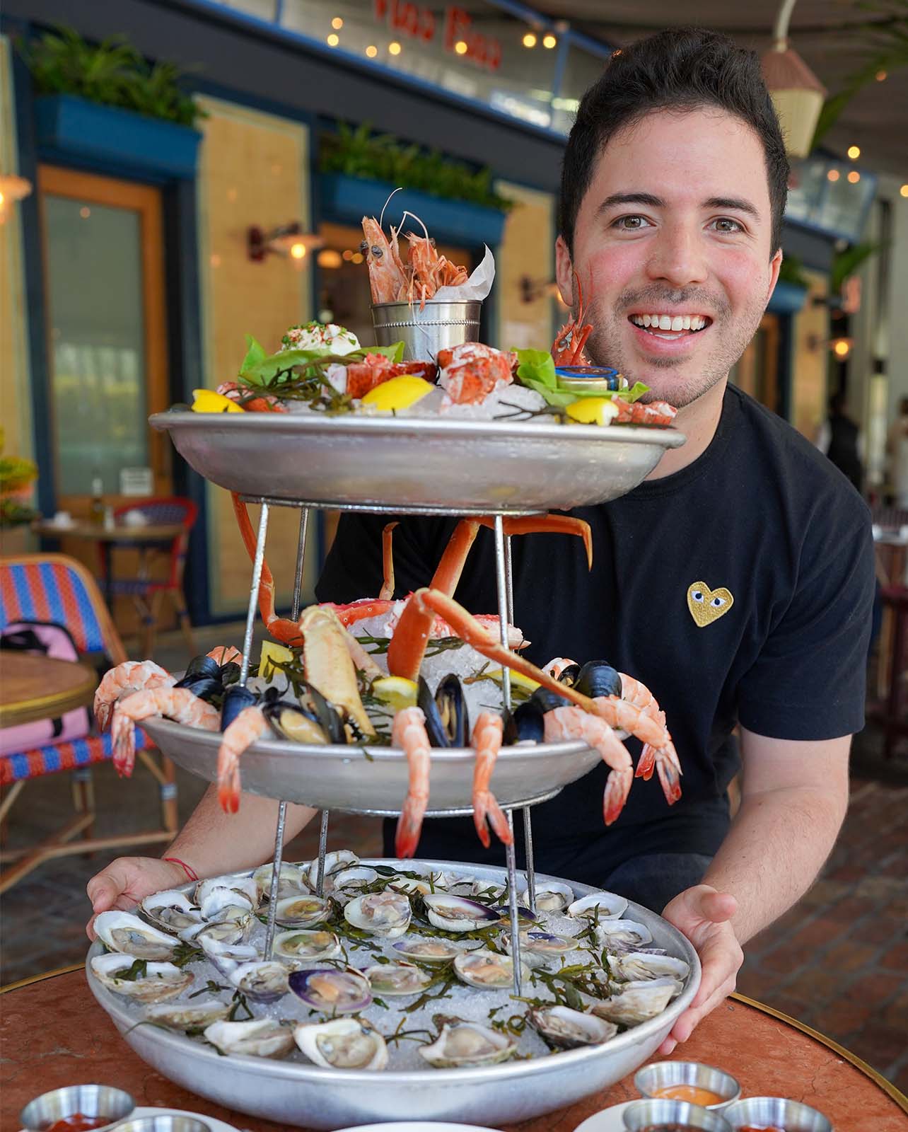 Man smiles standing beside a seafood tower