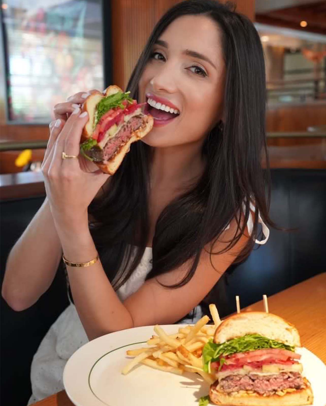 Woman smiles while holding up a cheeseburger
